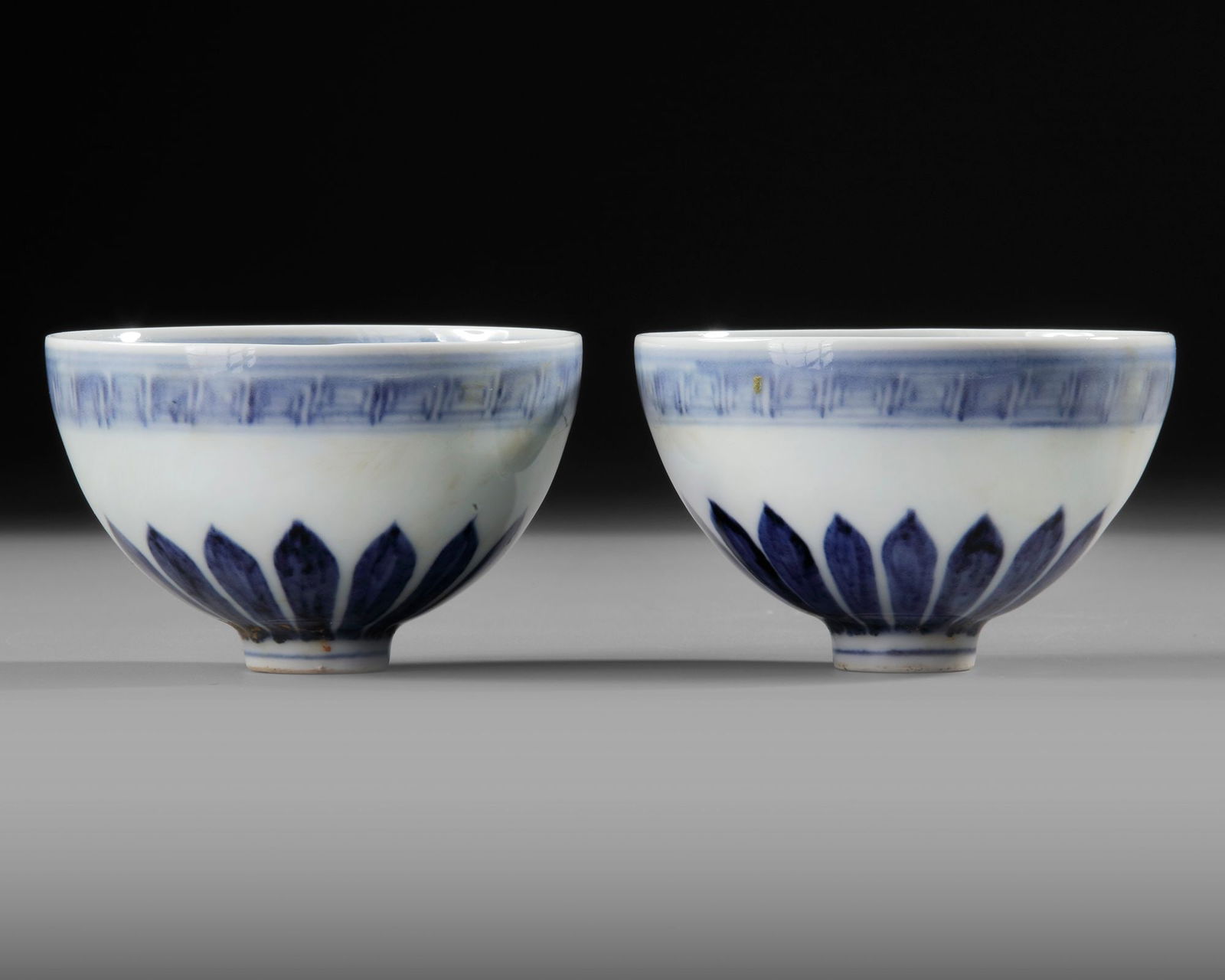 PAIR OF CHINESE BLUE AND WHITE â€?LOTUSâ€™ BOWLS, MING-STYLE, 20TH CENTURY: A finely painted pair of porcelain bowls decorated in rich underglaze cobalt blue, each featuring stylized lotus petals around the exterior and intricate floral scroll motifs to the interior. D.10 cm.