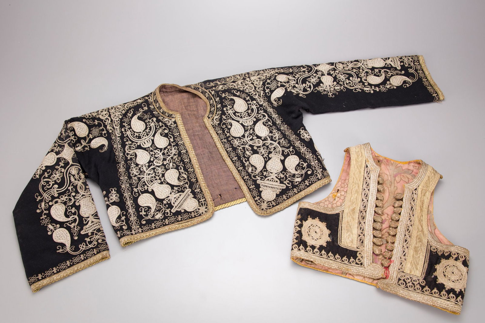 AN OTTOMAN WAISTCOAT, 20TH CENTURY: Of black velvet embroidered with metal thread and decorated with floral designs.Condition: some wear. ca. 140 by 40 cm.