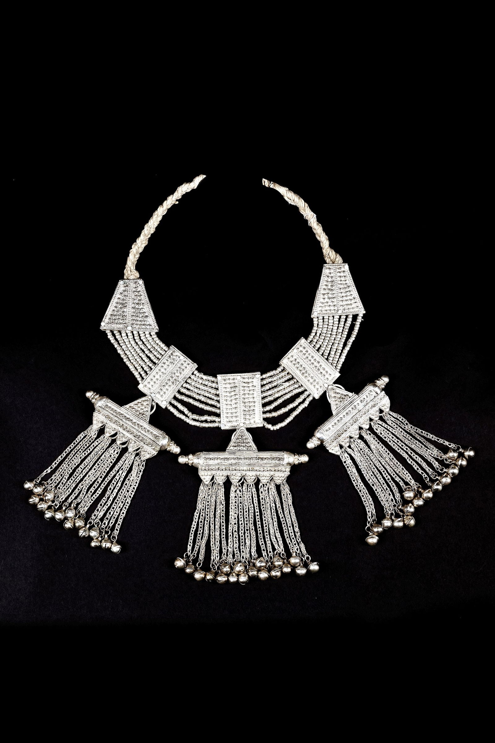 A SILVER NECKLACE, SAUDI ARABIA, 19TH CENTURY: Featuring multiple strands of fine beads, triangular plaques, and large pendants with cascading chains and bells. 37 by 29 cm. 926 gr. THE DR. SAAD AL-JADIR COLLECTION