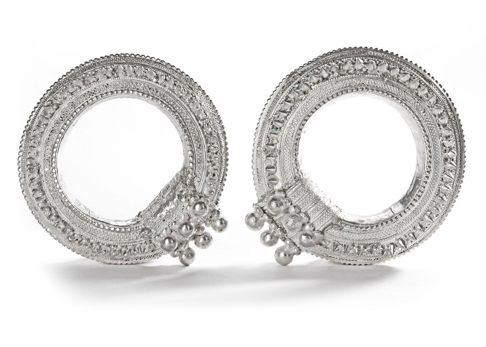 A PAIR OF BEDOUIN SILVER ANKLETS, SAUDI ARABIA, 20TH CENTURY: With intricate patterns and raised beadwork. 14 by 4 cm each. 759 gr.THE DR. SAAD AL-JADIR COLLECTION