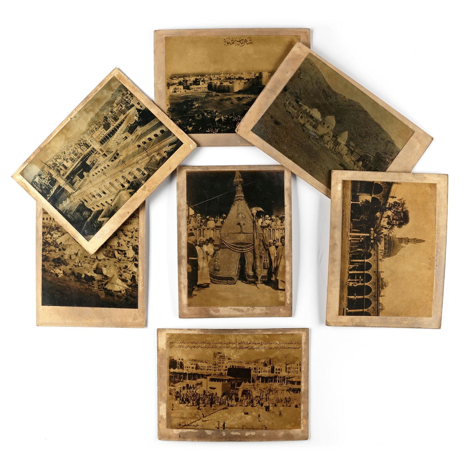 A COLLECTION OF SEVEN OLD PHOTOGRAPHS OF MECCA, MEDINA, THE MAHMAL AND THE HAJJ, EARLY 20TH CENTURY: Images of Mecca with prayers around the Kaaba with al-Salam gate, arrival of the Mahmal at Mecca, pilgrims' tents at Muna, a view of the city of Medina and the Prophet's mosque, a close view of al-Mas
