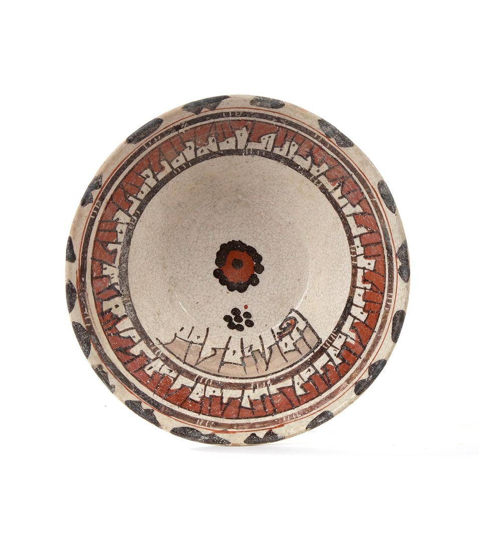 NISHAPUR SLIP-PAINTED POTTERY BOWL, 9TH-10TH CENTURY: With flaring sides, decorated in manganese-brown and red on a cream ground with a band of Kufic inscription around the sides, one side with a further band of inscription, the rosette in the middle, th