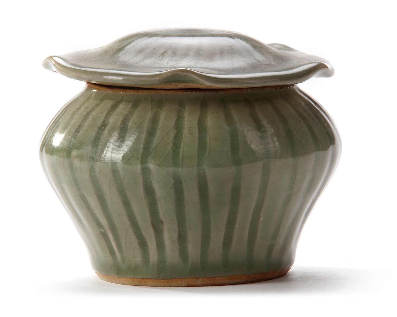 A CHINESE LONGQUAN CELADON â€?HUNDRED RIBâ€™ JAR AND â€?LOTUSâ€™ COVER, MING: The potted jar of compressed form, moulded with vertical ribs extending from below the short neck to the thick foot, the lobed cover in the form of a lotus leaf with similarly ribbed sides, both cover