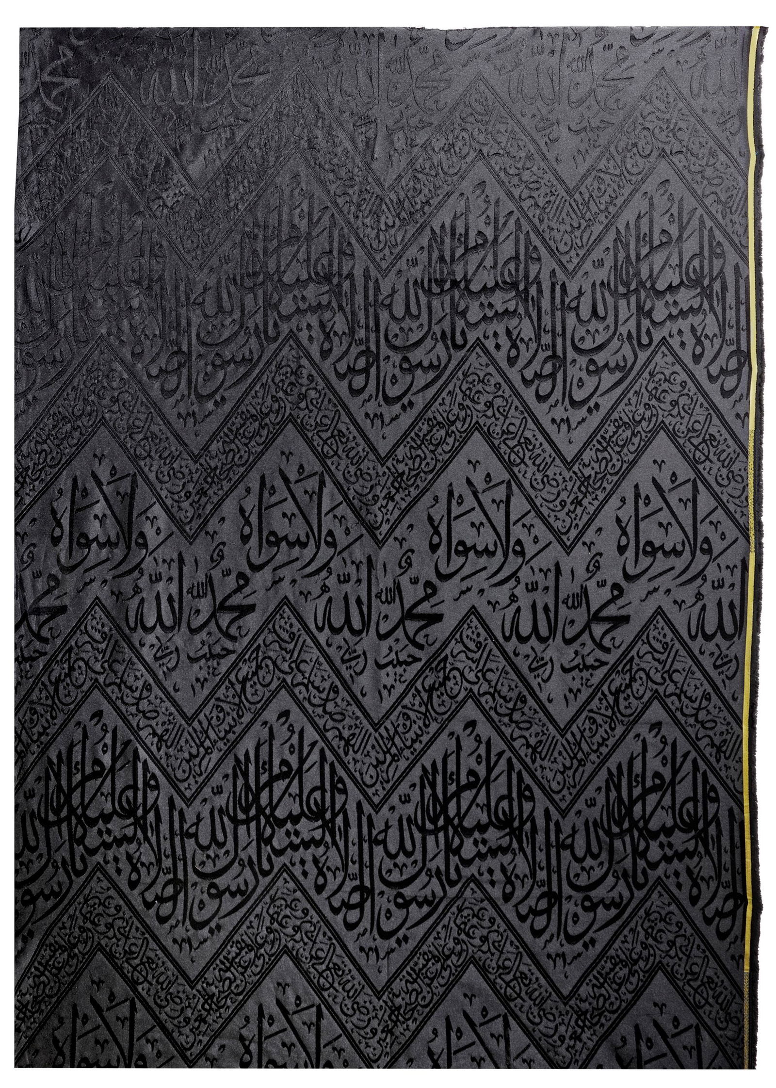 A BLACK KABAA KISWAH TEXTILE FRAGMENT, SAUDIA ARABIA, 20TH CENTURY: A fragment of the inner curtain of sacred kiswa for the inner wall of the Kabaa with an inscribed weave in silver-colored silk over a dark black ground. Embellished with a prominent inscription within