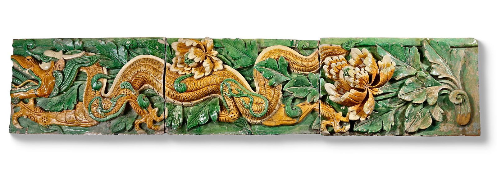 A SET OF THREE GREEN AND AMBER GLAZED ARCHITECTURAL TILES, CHINA, MING DYNASTY (1368-1644): The tiles are well modeled in high relief with the writhing body of a large scaly dragon and lotus flowers.Oxford TL tested.Provenance: private collection Belgium.