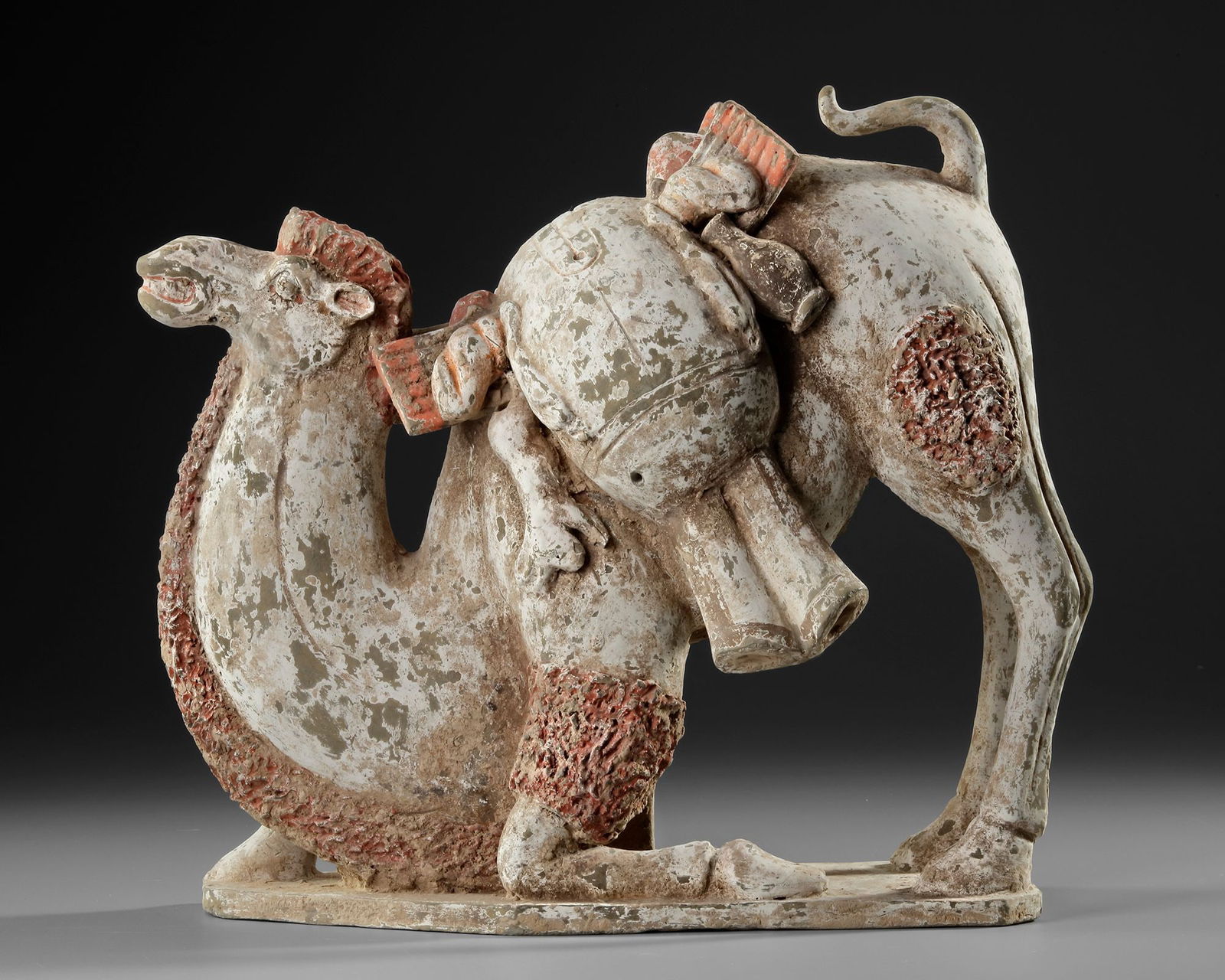 A PAINTED TERRACOTTA KNEELING CAMEL WITH SADDLE PACK, CHINA, TANG DYNASTY (618-906 AD) (1 of 6)
