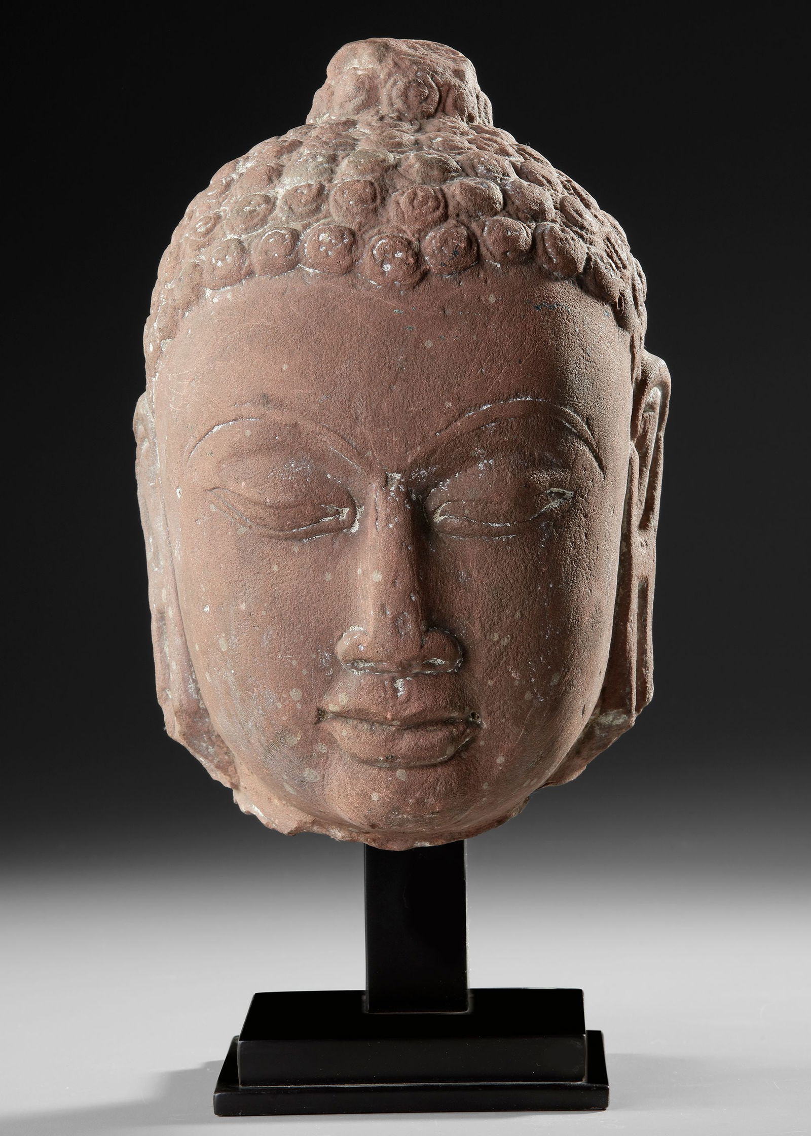 A BUDDHA HEAD, GUPTA PERIOD (4THâ€“6TH CENTURY AD): Stone sculpture of a Buddha head from India . The serene expression, softly modeled features, and stylized curled hair reflect the spiritual idealism characteristic of Gupta Buddhist sculpture. The el