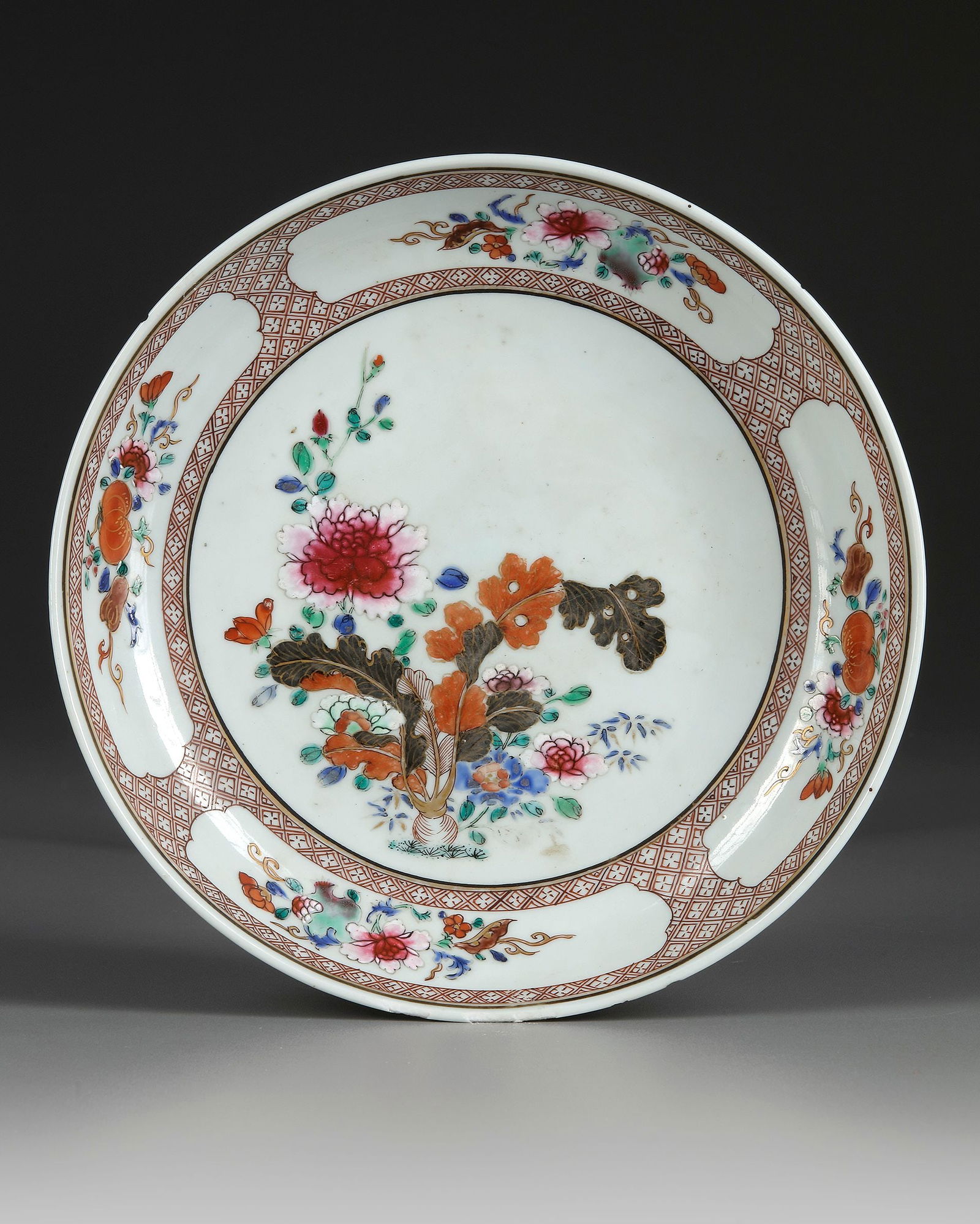 A CHINESE FAMILLE ROSE DISH, 18TH CENTURY: A Chinese porcelain dish decorated in famille rose enamels with a central roundel enclosing chrysanthemums and peonies blossoming branches, the sides with cartouches contains fruits and flower heads.