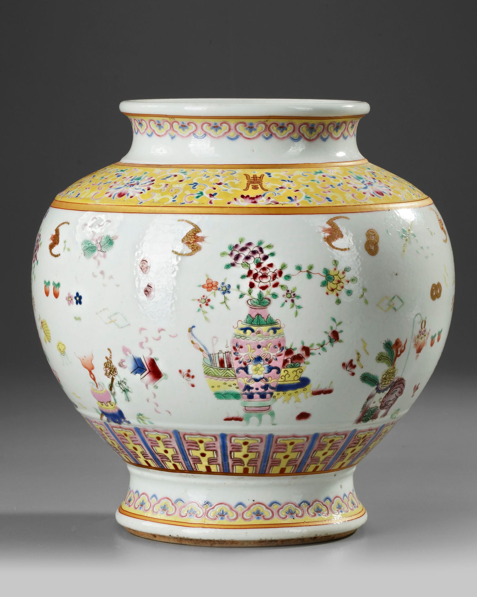 A CHINESE FAMILLE ROSE JAR, 19TH-20TH CENTURY: A Chinese porcelain jar, decorated in famille rose enamels around the body with precious items, above a petal lappet border. The shoulder is stylized with a diaper band enclosing Chinese characters am