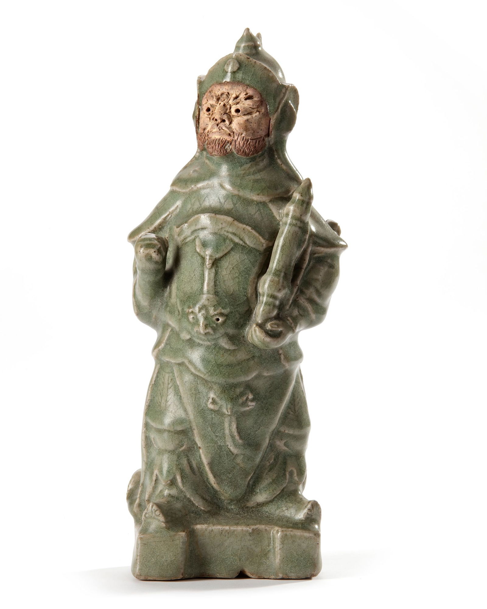 A CHINESE CELADON GUAN YU FIGURE, MING DYNASTY, 15TH CENTURY: A Chinese celadon figure of the god of war, Guan Yu, covered with a light green glaze to the foot, semi-hollow base with an unglazed foot-rim burnt red, face left in biscuit. Height 24.8 cm.