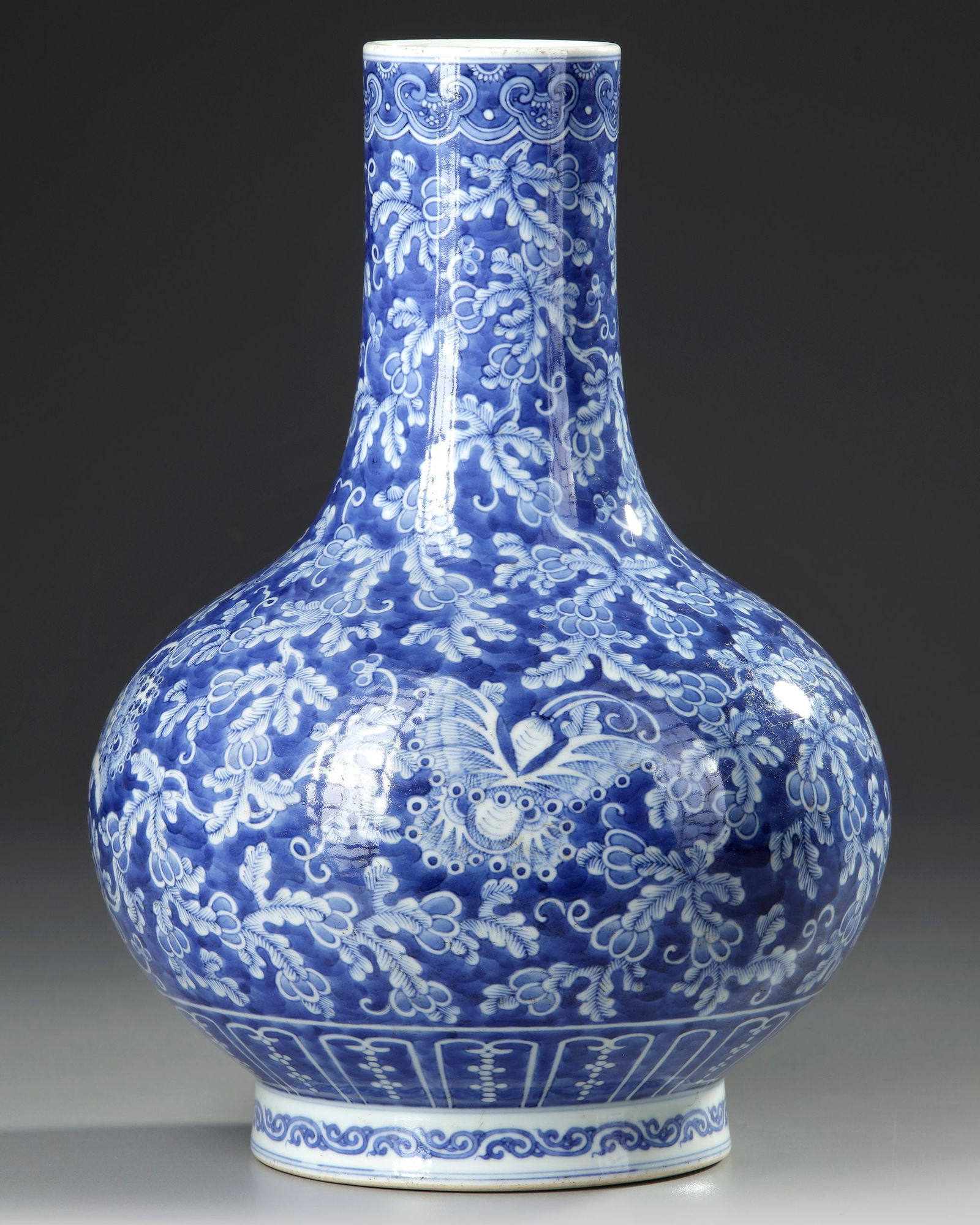 A CHINESE BLUE AND WHITE BOTTLE VASE, 19TH-20TH CENTURY: A Chinese bottle vase decorated in reverse blue with elegant butterflies amongst foliage, set between a band of ruyi heads to the rim and a lappet border to the base. The bottom with a Chinese Qianlon