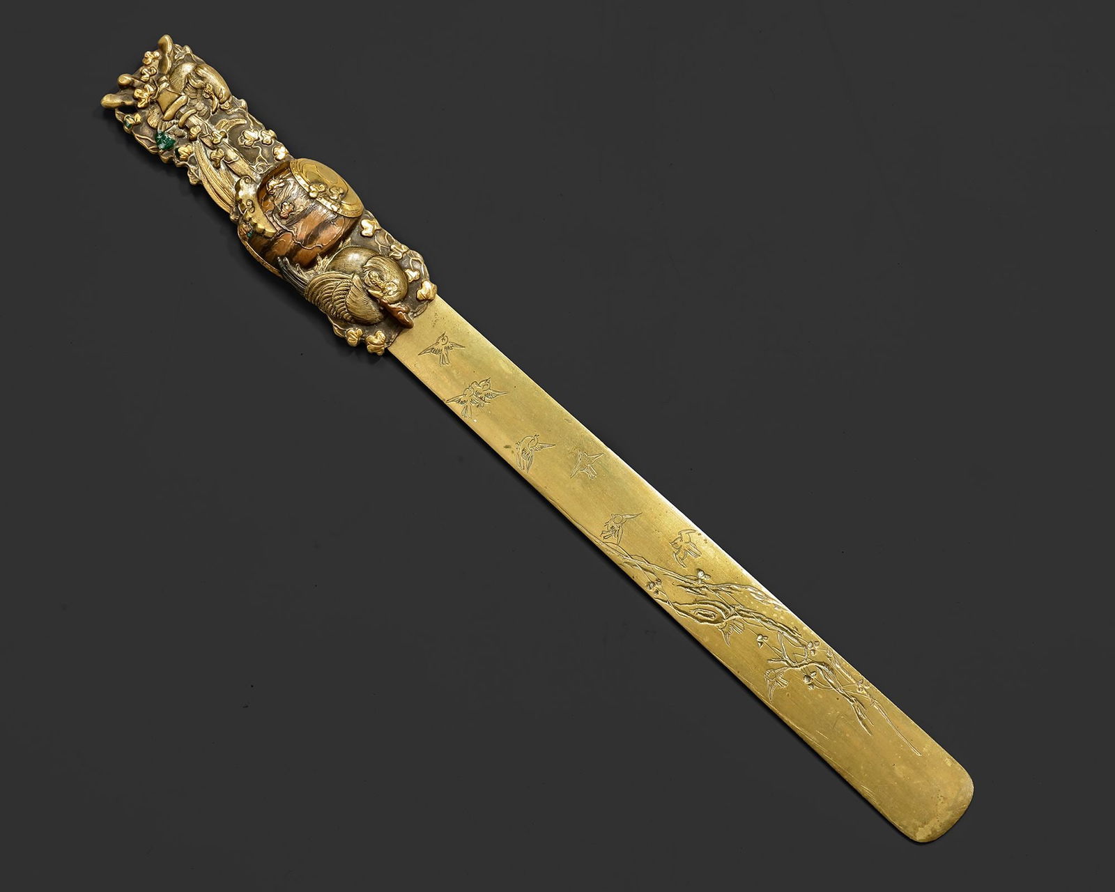 A JAPANESE LETTER OPENER, MEIJI PERIOD (1868â€“1912): Finely worked letter opener with a long, spatulate blade engraved with birds in flight and a flowering branch. The sculptural handle is richly ornamented in high relief with Daikoku, the god of wealth