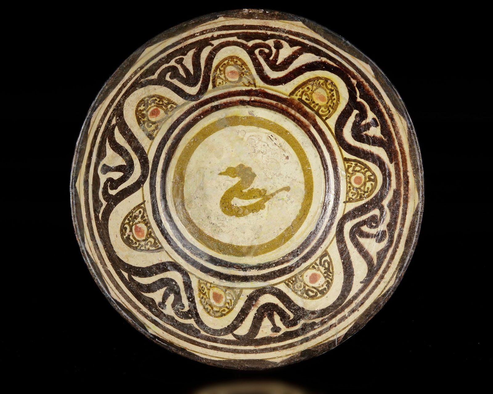 A NISHAPUR PAINTED POTTERY BOWL, PERSIA 10TH CENTURY: A pottery bowl with broad, shallow hemispherical form rising from a small ring foot, with gently flaring walls and a slightly everted rim. The vessel is wheel-thrown in buff earthenware and covered wi