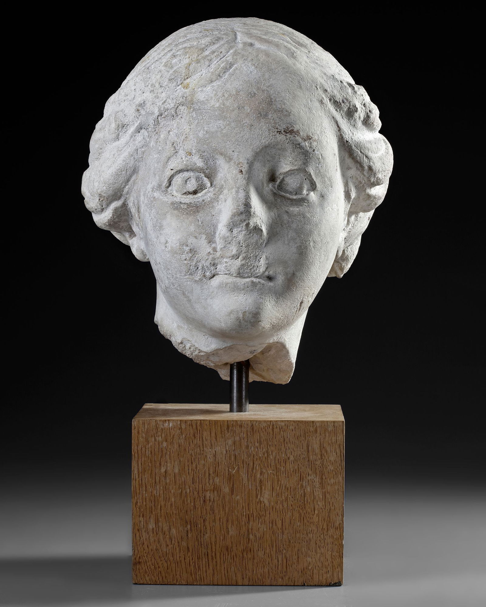 A MARBLE FEMALE HEAD, 17TH-18TH CENTURY: Head representing a woman whose wavy hair is girded with a headband. Marble stone. Height: 26 cm.
