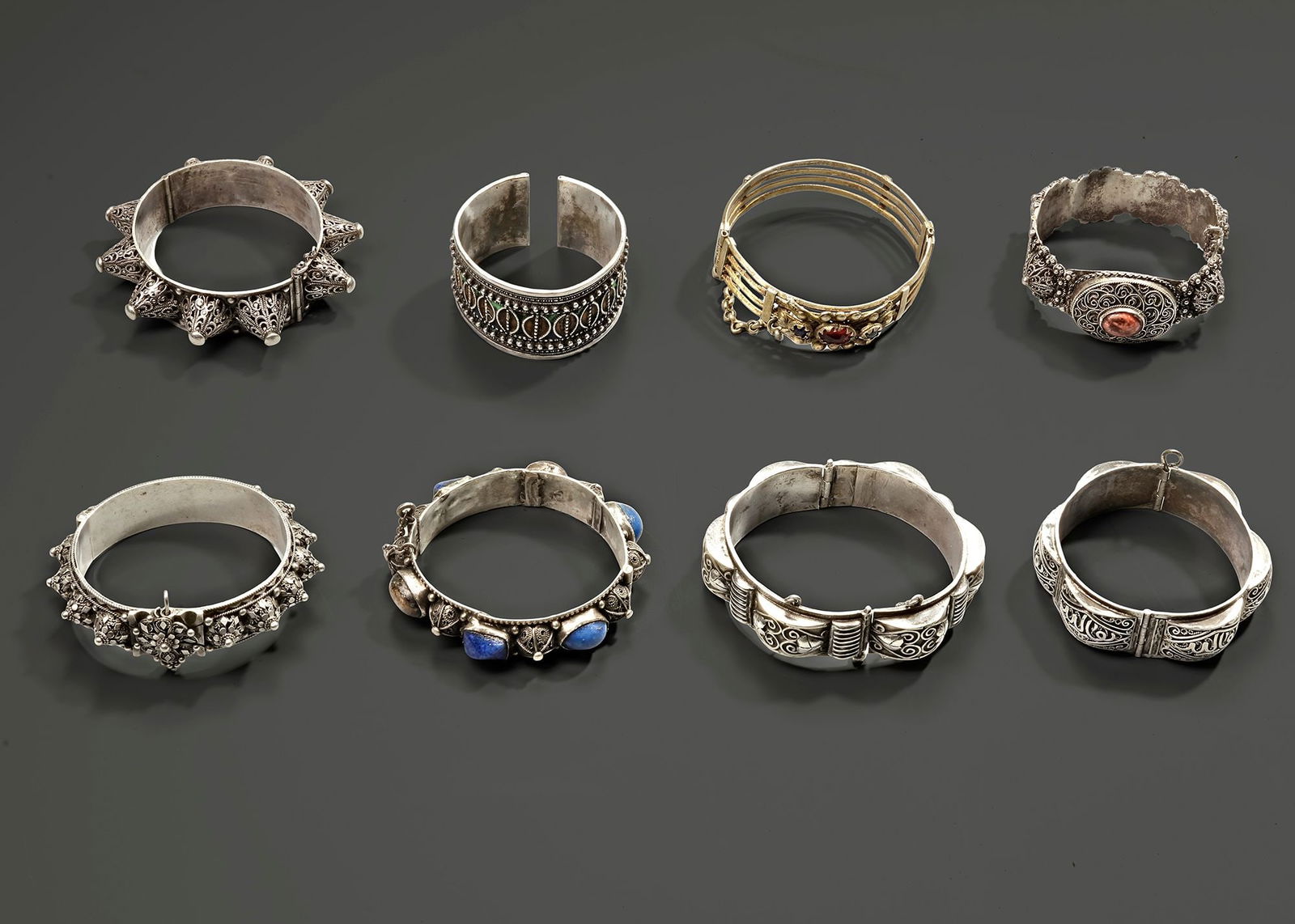 A GROUP OF EIGHT BRACELETS, 20TH CENTURY: A collection of eight ornate silver bracelets from Morocco, Yemen, Saudi Arabia, and Oman, dating back to the 19th century. Each piece showcases intricate craftsmanship, traditional motifs, and region