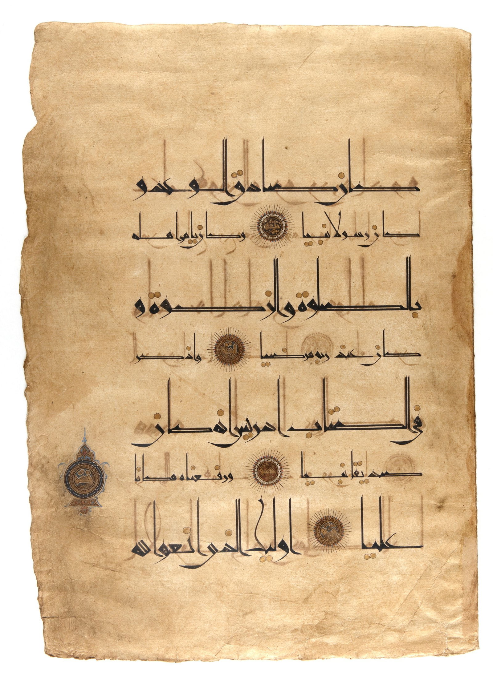 A QURAN LEAF IN EASTERN KUFIC SCRIPT ON PAPER, PERSIA, 11TH-12TH CENTURY: Arabic manuscript on paper, 7 lines to the page, written in elegant Eastern Kufic in black ink. Diacritical marks rendered as gold dots outlined in black. Verses separated by finely executed gold rose