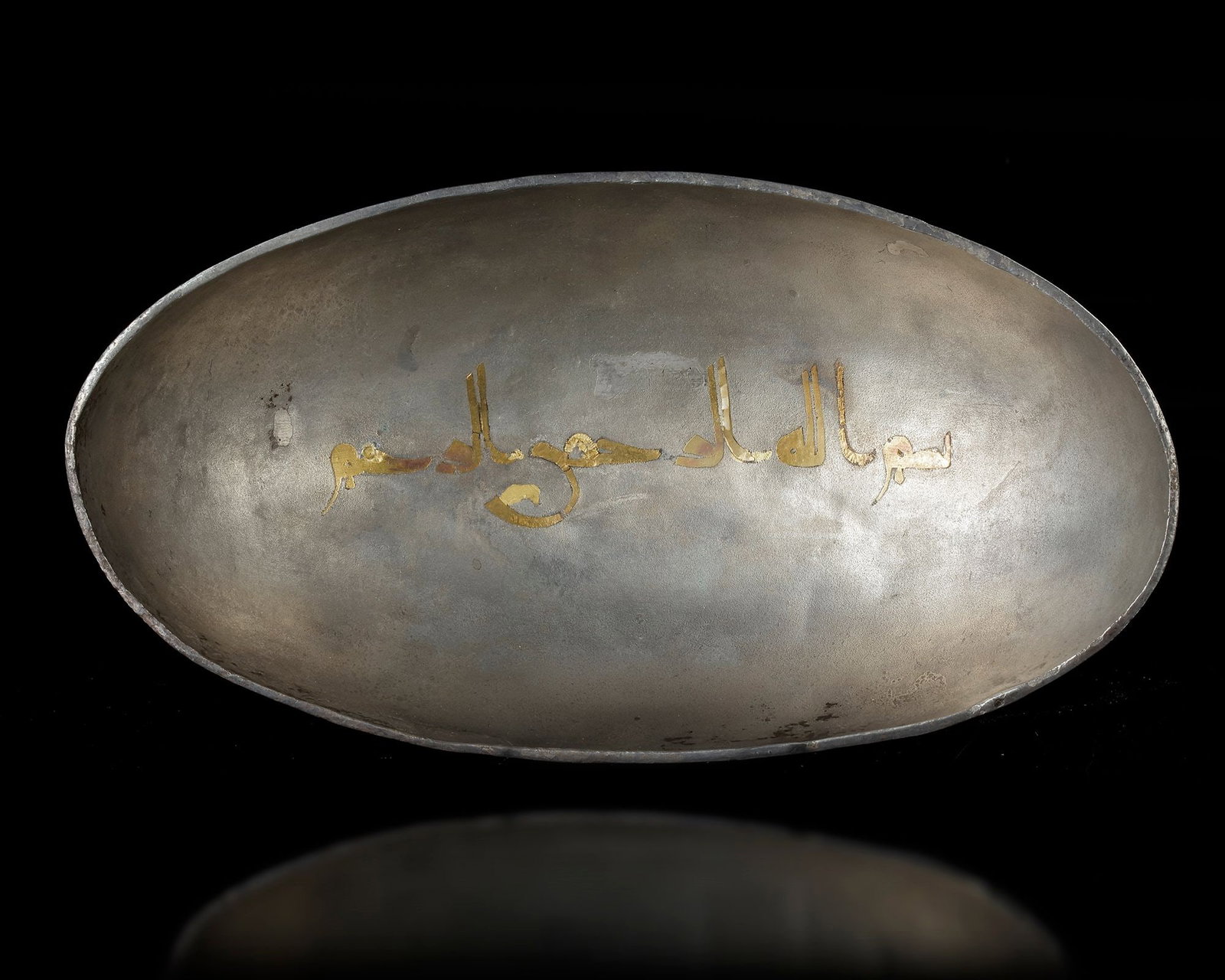 A SASANIAN SILVER BOWL WITH ISLAMIC INSCRIPTION, CIRCA 5THâ€“7TH CENTURY AD: A finely wrought Sasanian silver bowl, broad and softly oval in profile, its subtly hammered surface catching the light with a quiet, silvery sheen. The rim is encircled by a delicate gilded interlace