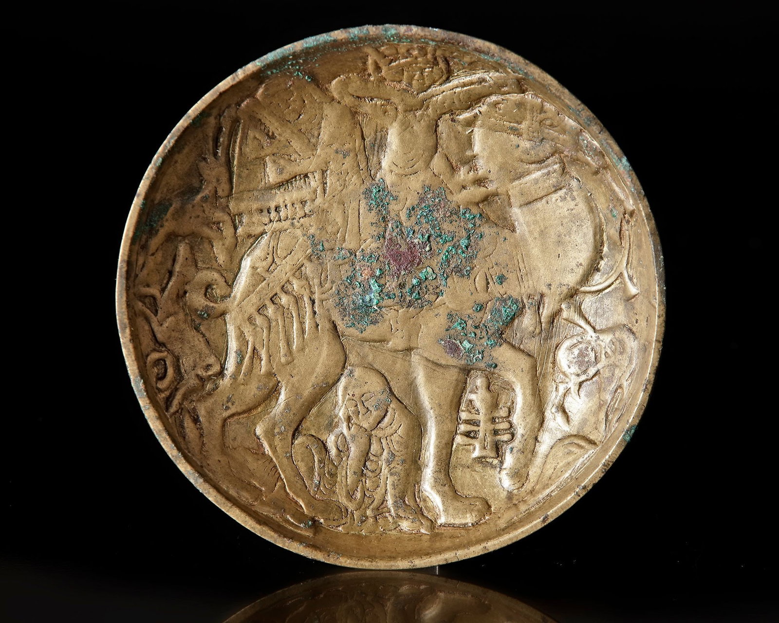 A GHAZNAVID HIGH-TIN BRONZE FIGURAL BOWL, EASTERN PERSIA, 11TH CENTURY: A rare cast Ghaznavid high-tin bronze bowl of shallow circular form with gently rising sides and a flat base. The exterior is plain save for lightly incised concentric rings at the base, while the int