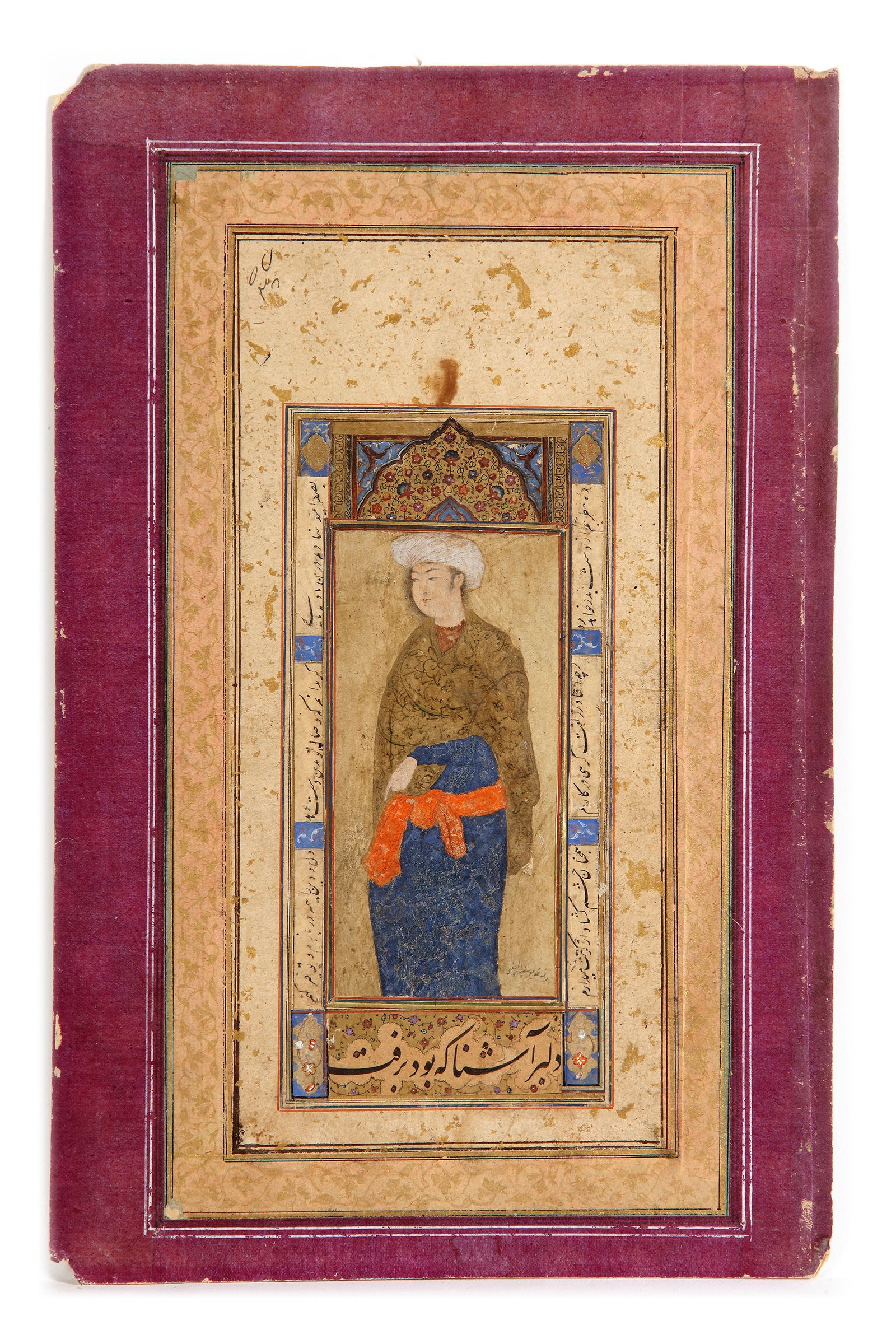 A SAFAVID PORTRAIT OF A YOUNG MAN, THE CALLIGRAPHY SIGNED MOHAMMED YUSEF AL-HUSAYNI, 17TH CENTURY: Gouache heightened with gold on paper, depicting a young man dressed in flowing blue robes, cinched at the waist with an orange sash. He wears a golden-brown shawl or outer garment embellished with de