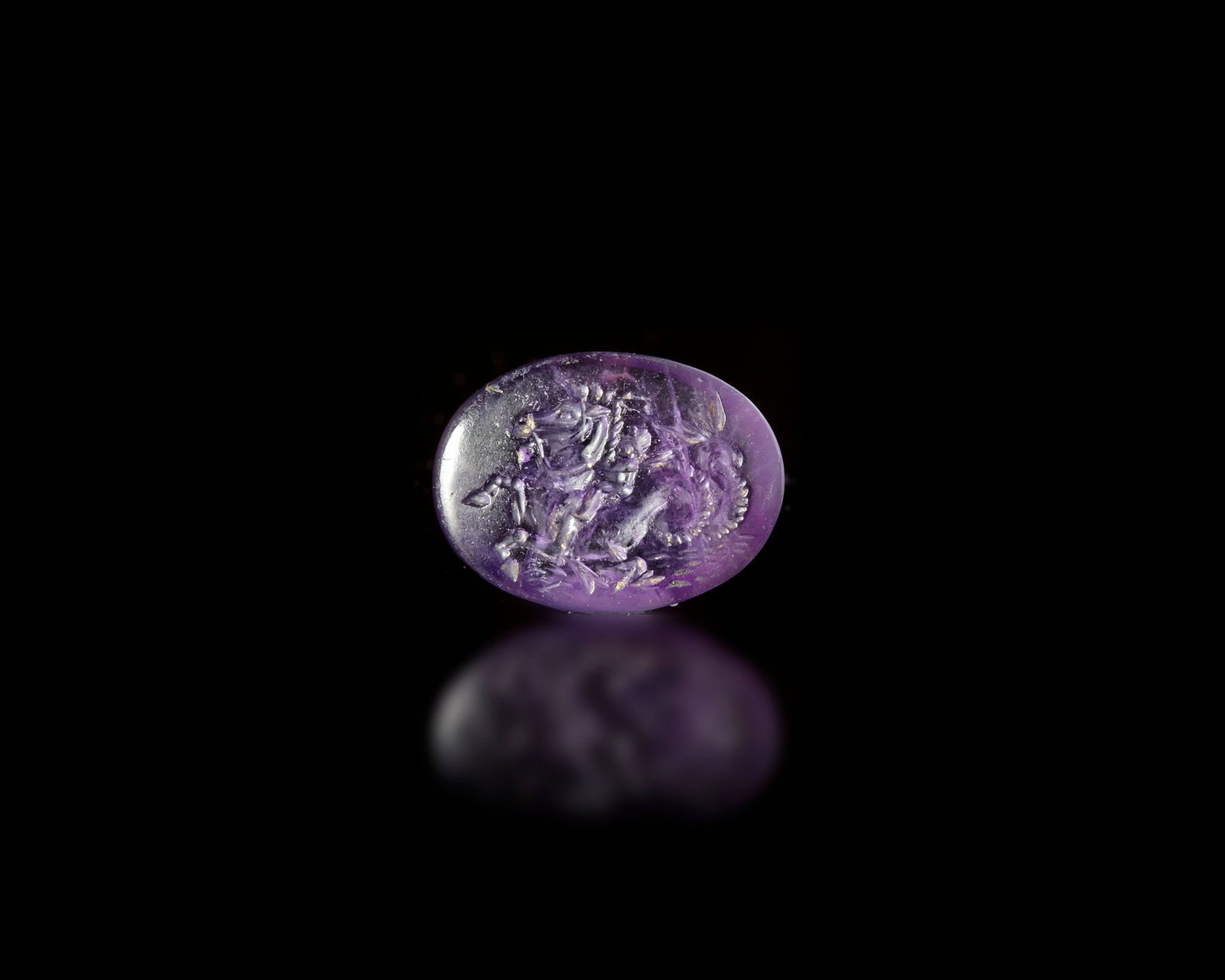 A ROMAN AMETHYST INTAGLIO OF EROS ON A SEA HORSE, 1ST- 2ND CENTURY AD: Roman amethyst intaglio intricately engraved with Eros seated upon a sea horse, a charming fusion of love symbolism and marine mythology. 12 by 18 mm.
