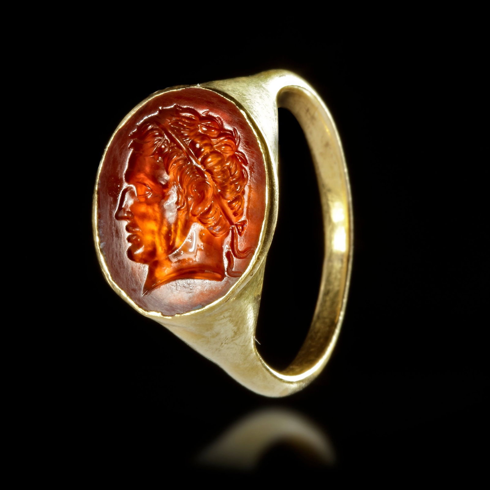 A GOLD RING WITH A CARNELIAN INTAGLIO WITH THE PORTRAIT OF A HELLENISTIC RULER, 2ND/3RD CENTURY BC: A hollow gold ring with an carnelian intaglio of a Hellenistic ruler ( Seleucid or Ptolemaic? ) wearing a diadem. A finely rendered portrait of a Hellenistic ruler. Size of intaglio : 15 mm. Ring : 23
