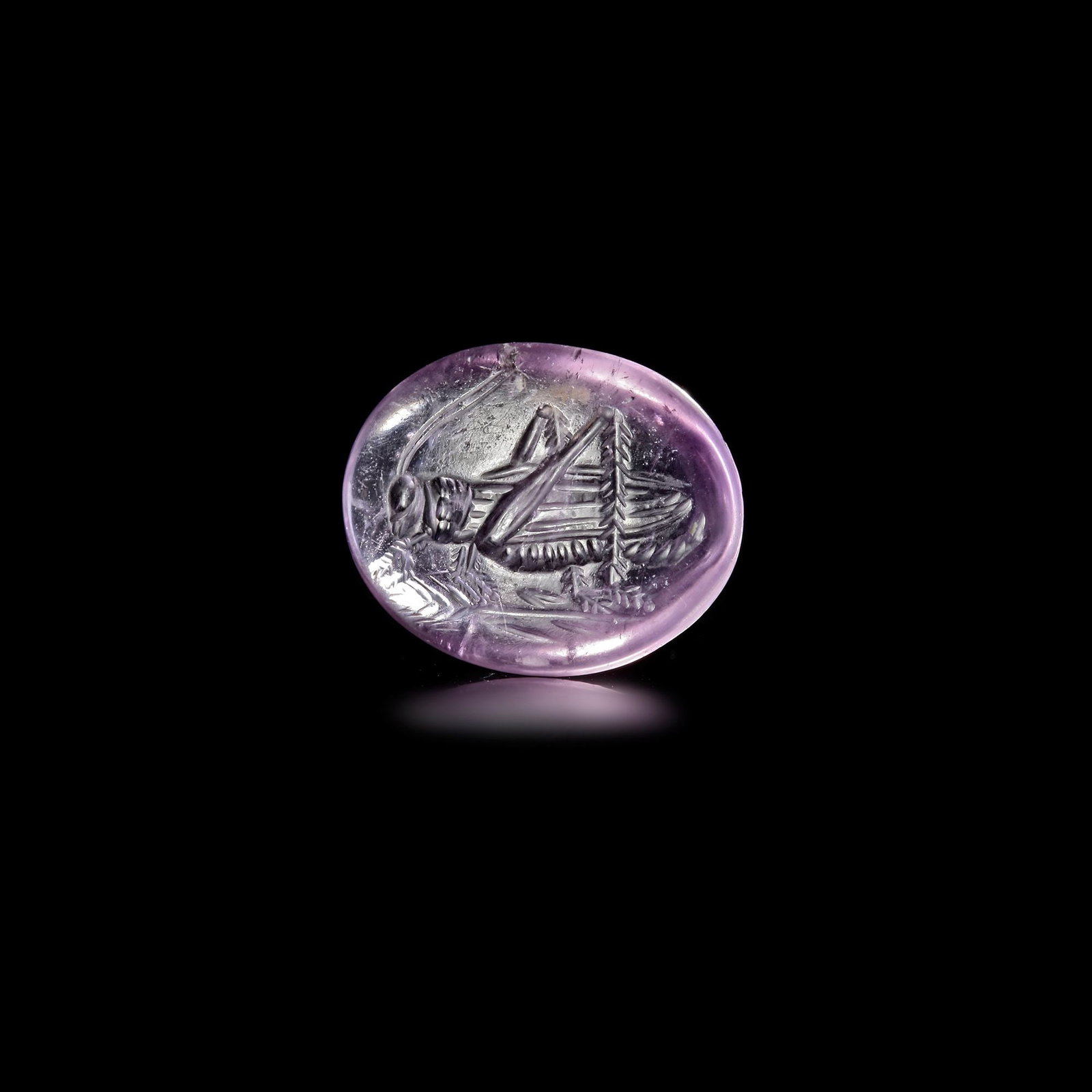 A HELLENISTIC AMETHYST GEM WITH GRASSHOPPER 200â€“100 BC: This finely carved Hellenistic intaglio, made of lustrous amethyst, features a detailed depiction of a grasshopper, rendered with exquisite naturalism. The grasshopper, delicately incised into the sur