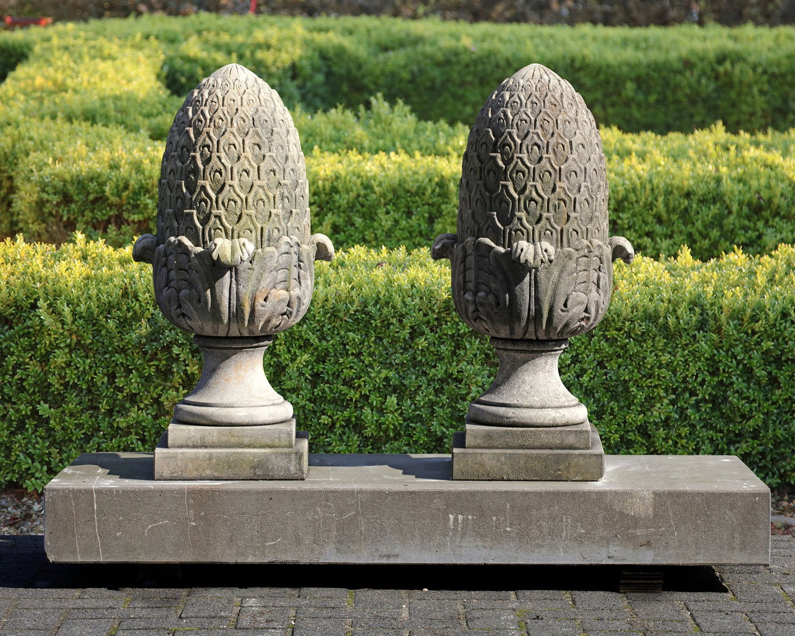 A PAIR OF CARVED LIMESTONE PIER FINIALS, 20TH CENTURY: Height 80 cm. Plinth 30 by 30 cm.