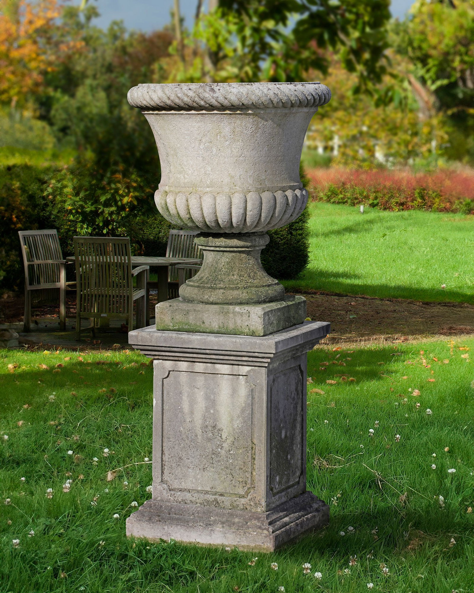 A CARVED LIMESTONE GARDEN URN, 20TH CENTURY: With eververted cable moulded rim above a semi lobed body. Height overall 150 cm. Diameter 67 cm. Pedestal height 70 by 51 by 48 cm.