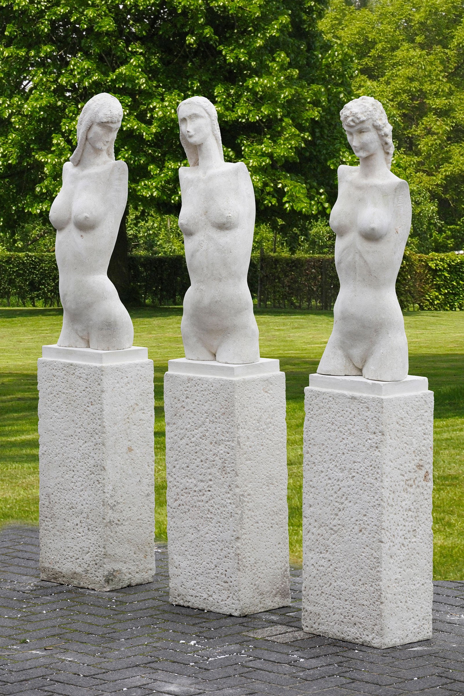 SET OF THREE MODERN FEMALE SCULPTURES, INSPIRED GIACOMETTI: Three modern, white stone sculptures of female torsos, each placed on a tall, rectangular pedestal. Due to this abstraction, the focus lies on the form and line of the body rather than on individual f