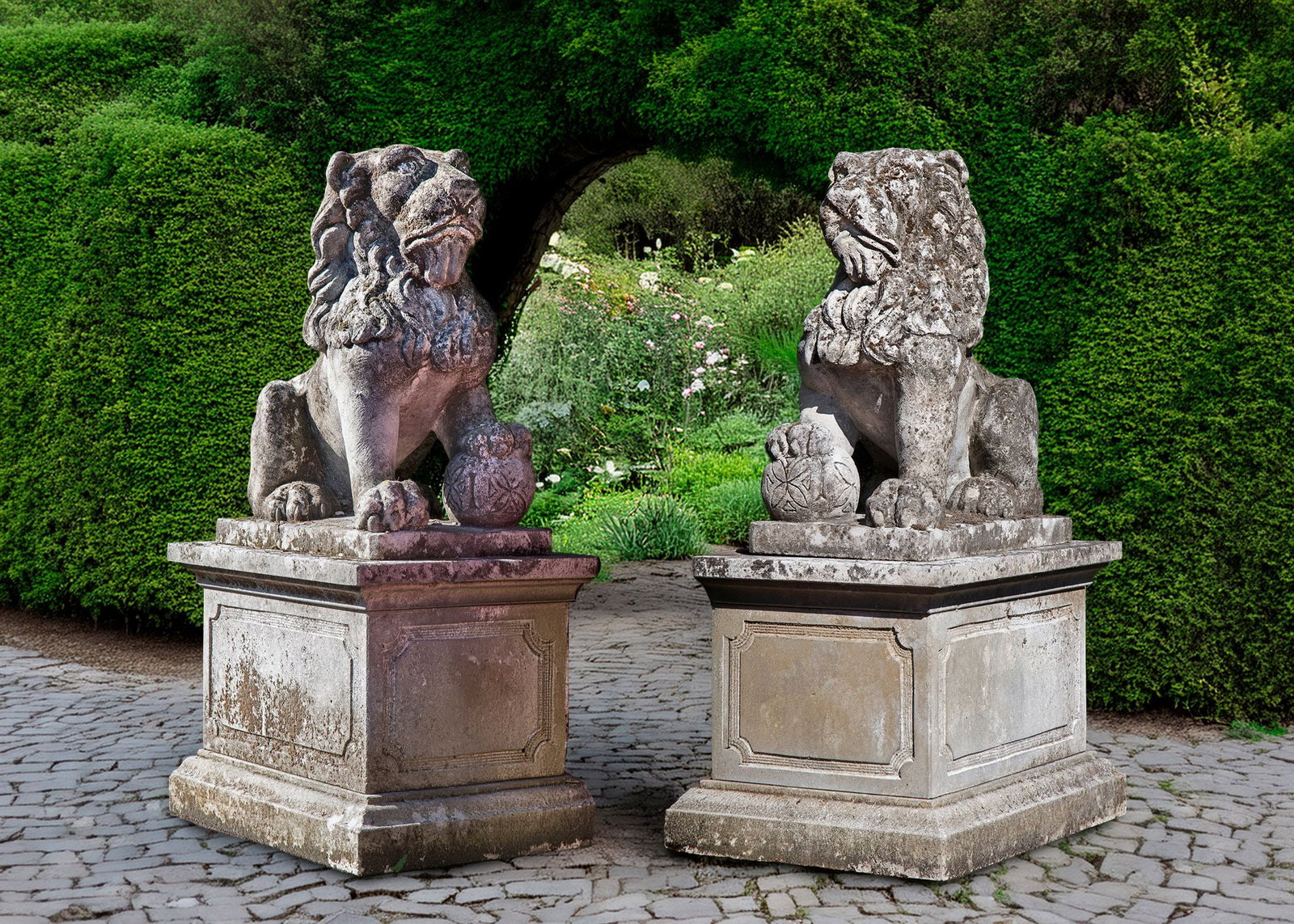 A PAIR OF SCULPTED LIMESTONE MODELS OF LIONS ON PEDESTALS, SECOND HALF 20TH CENTURY: Modelled opposing and each with one raised paw resting on an orb. Height 70 cm. Width 35 cm. Depth 56 cm. Atop square section pedestals with panel sides, height 50 cm., width 48 cm., depth 70 cm. Heig