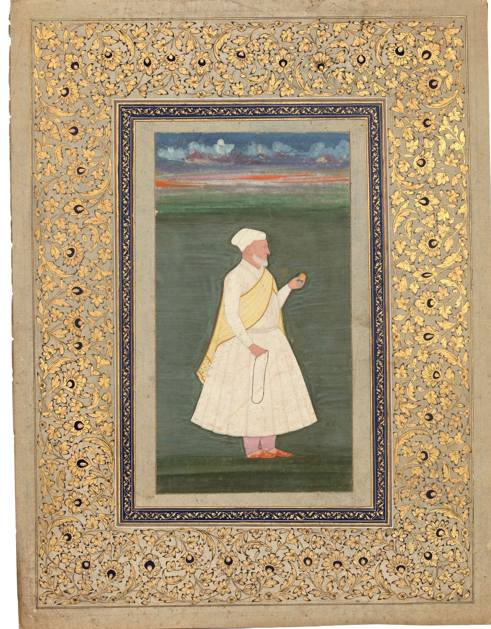 A NOBLEMAN WITH FRUIT, 19TH CENTURY: A 19th-century Indian miniature painting depicting a dignified nobleman dressed in white garments, standing in a landscape while holding a small fruit and prayer beads. The figure is framed by an orna
