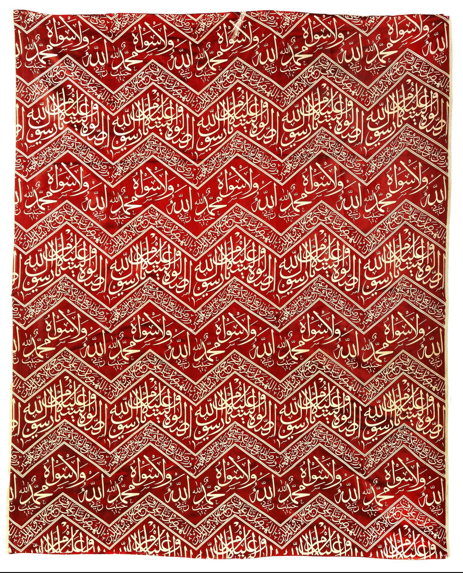 AN OTTOMAN RED-GROUND CALLIGRAPHIC SILK LAMPAS PANEL, TURKEY, 20TH CENTURY: A fragment of silk hanging panel of the inner kiswa, with an inscribed weave in cream color over a red silk ground. 105 by 87 cm. Inscription within a broad border in thuluth script of praise of the p