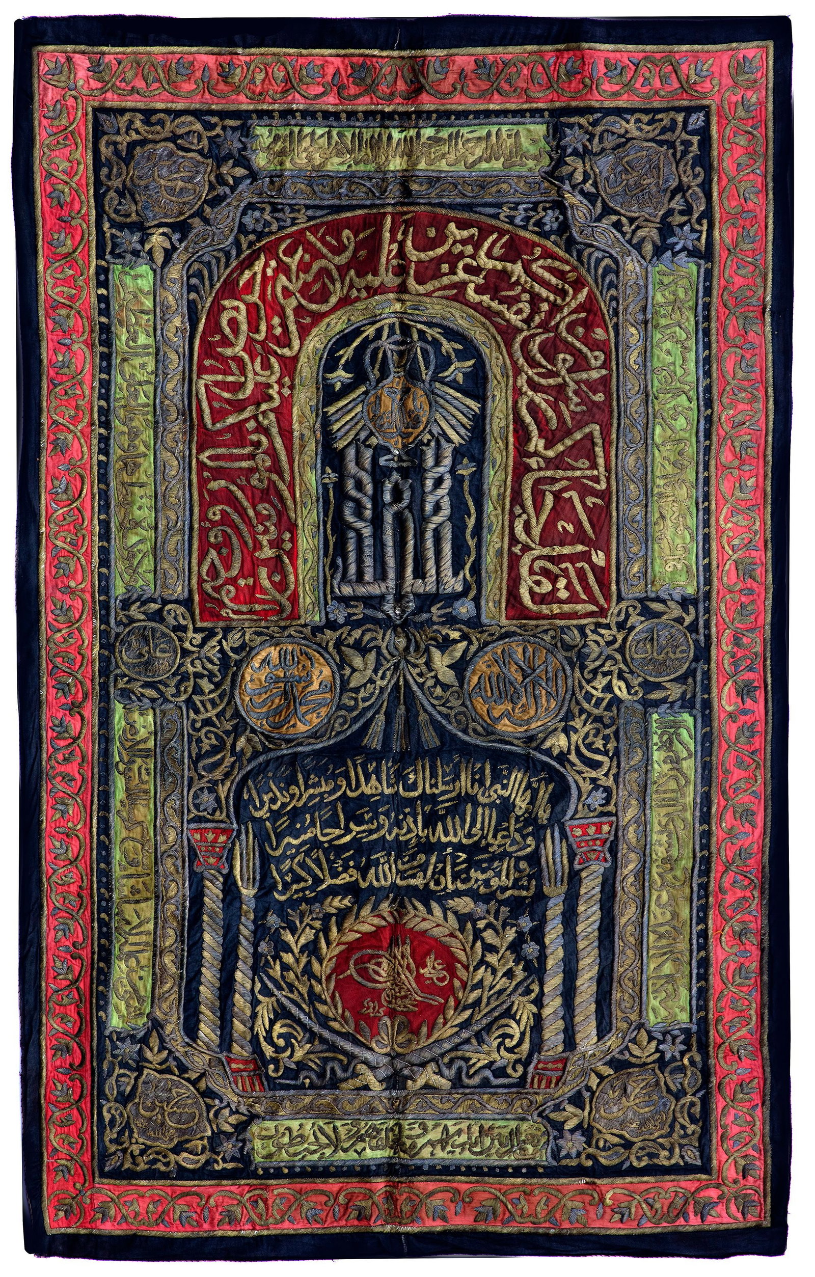 AN OTTOMAN METAL THREAD EMBROIDERED CURTAIN WITH THE TUGHRA OF MAHMUD II (AH 1223-1255/ AD: Of rectangular form, the black field with applied thick silver and gilt embroidery forming calligraphic cartouches surrounding an inner mihrab with columns and mosque lamp .The outer border is embelli