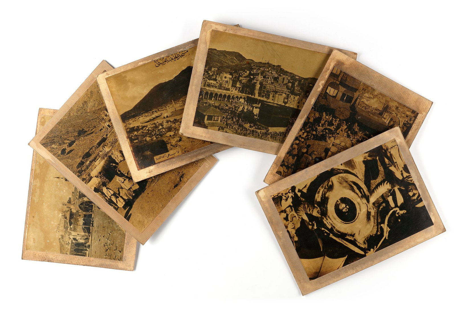 A COLLECTION OF SEVEN OLD PHOTOGRAPHS OF MECCA, MUNA AND THE HAJJ, EARLY 20TH CENTURY: Image of vast crowds of pilgrims in the square and cloisters of al-Masjid al-Haram with house of Mecca in the background, pilgrims' tents at Muna, a view people visiting Al-Baqi Cemetery, prayers arou