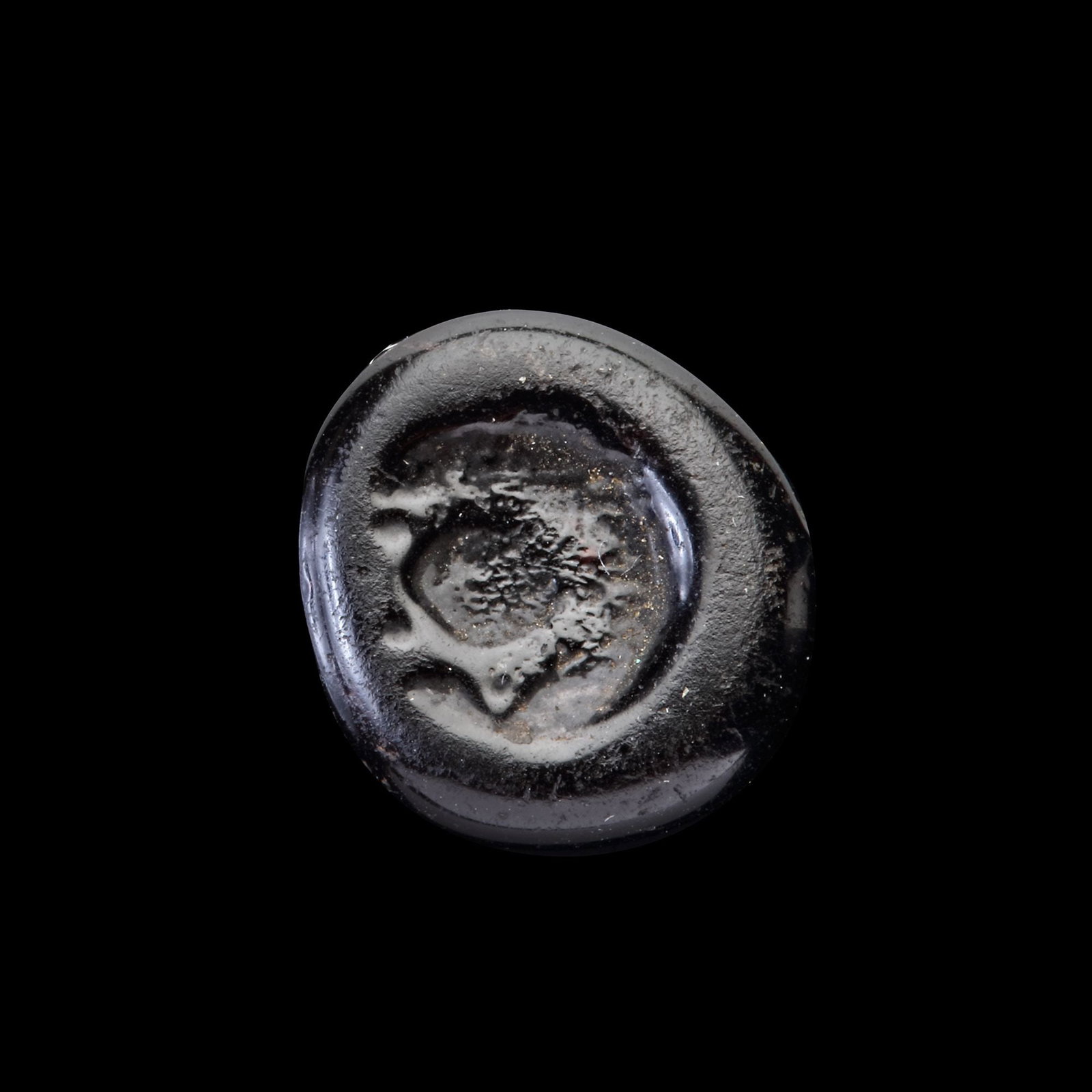 AN EARLY ISLAMIC GLASS WEIGHT OF HALF DIRHAM, 10TH-11TH CENTURY: Glass weight, moulded and stamped, opaque dark-black in colour, citing in the centre with the star of Solomon. 1.543g, 1.4 mm. coin weight: half dirham.