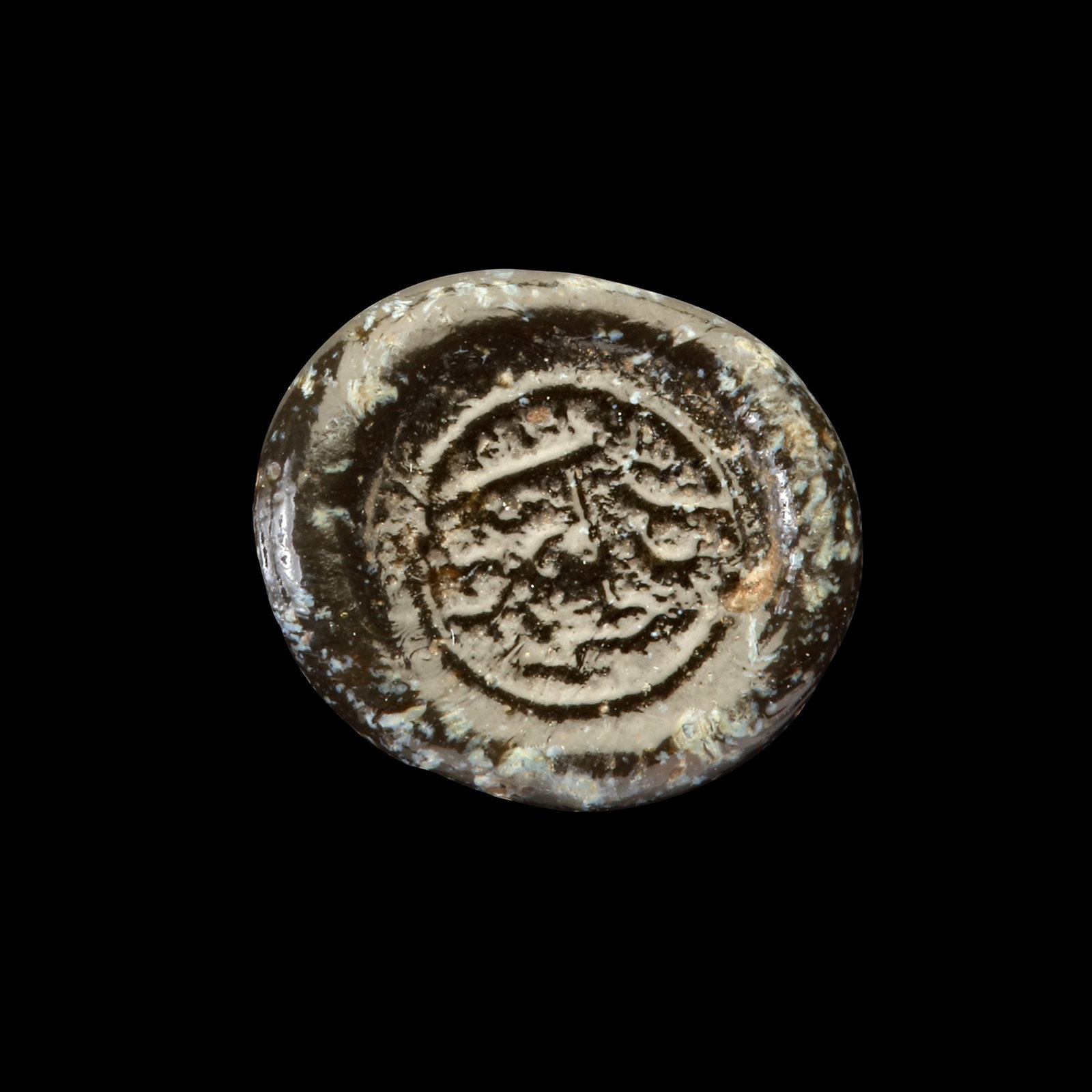 AN EARLY ISLAMIC GLASS WEIGHT OF QUARTER DIRHAM, 10TH-11TH CENTURY: Glass weight, moulded and stamped, opaque black in colour, citing in the centre with undeciphered Arabic text. 0.744g, 13 mm. coin weight: quarter dirham.