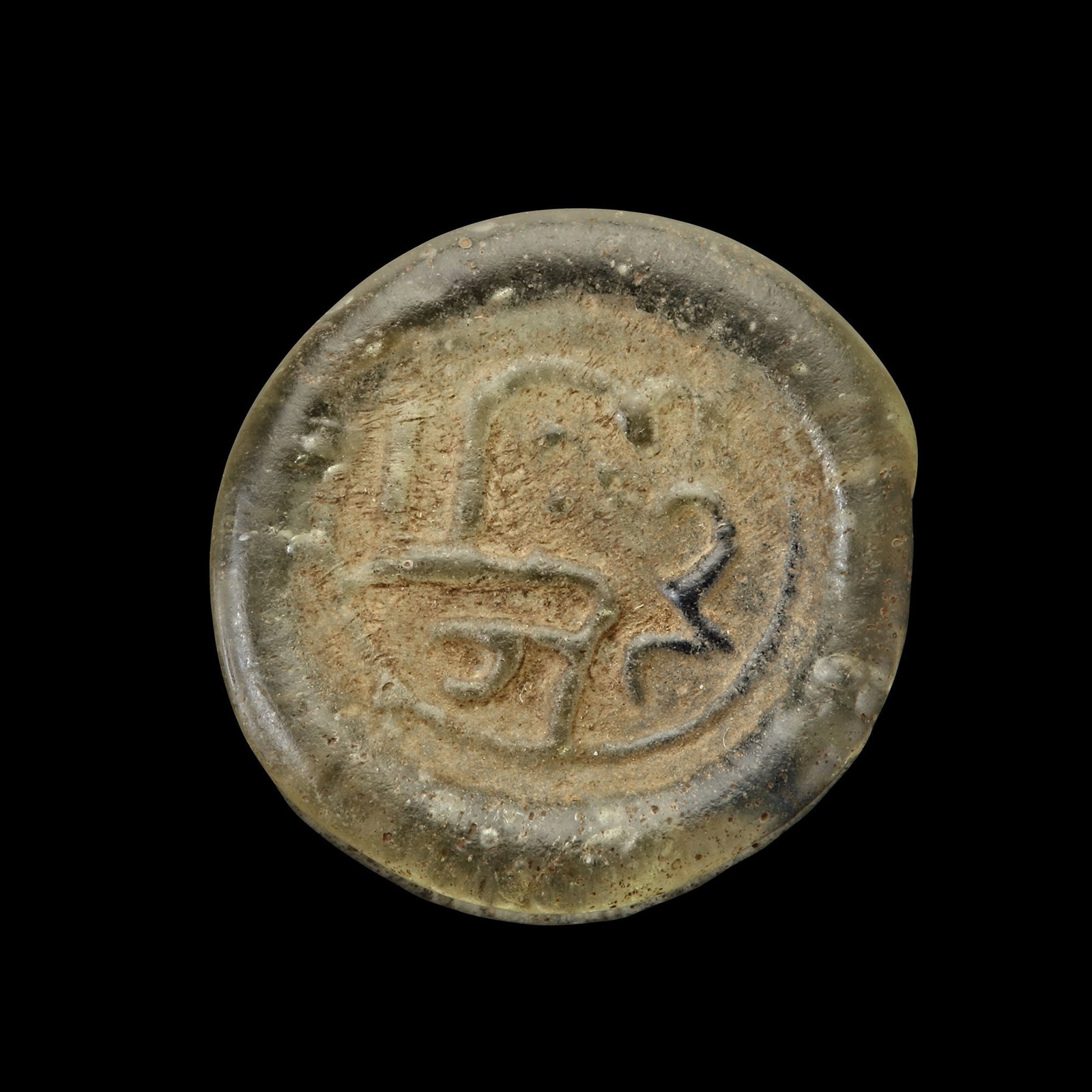 AN EARLY ISLAMIC GLASS WEIGHT OF DIRHAM,10TH-11TH CENTURY: Glass weight, moulded and stamped, transparent greenish-white in colour with blue splash, citing in the centre with " Ali Al-Suwajdi". 3.022g, 22.3 mm. coin weight: dirham. LP 1891/339-N 152
