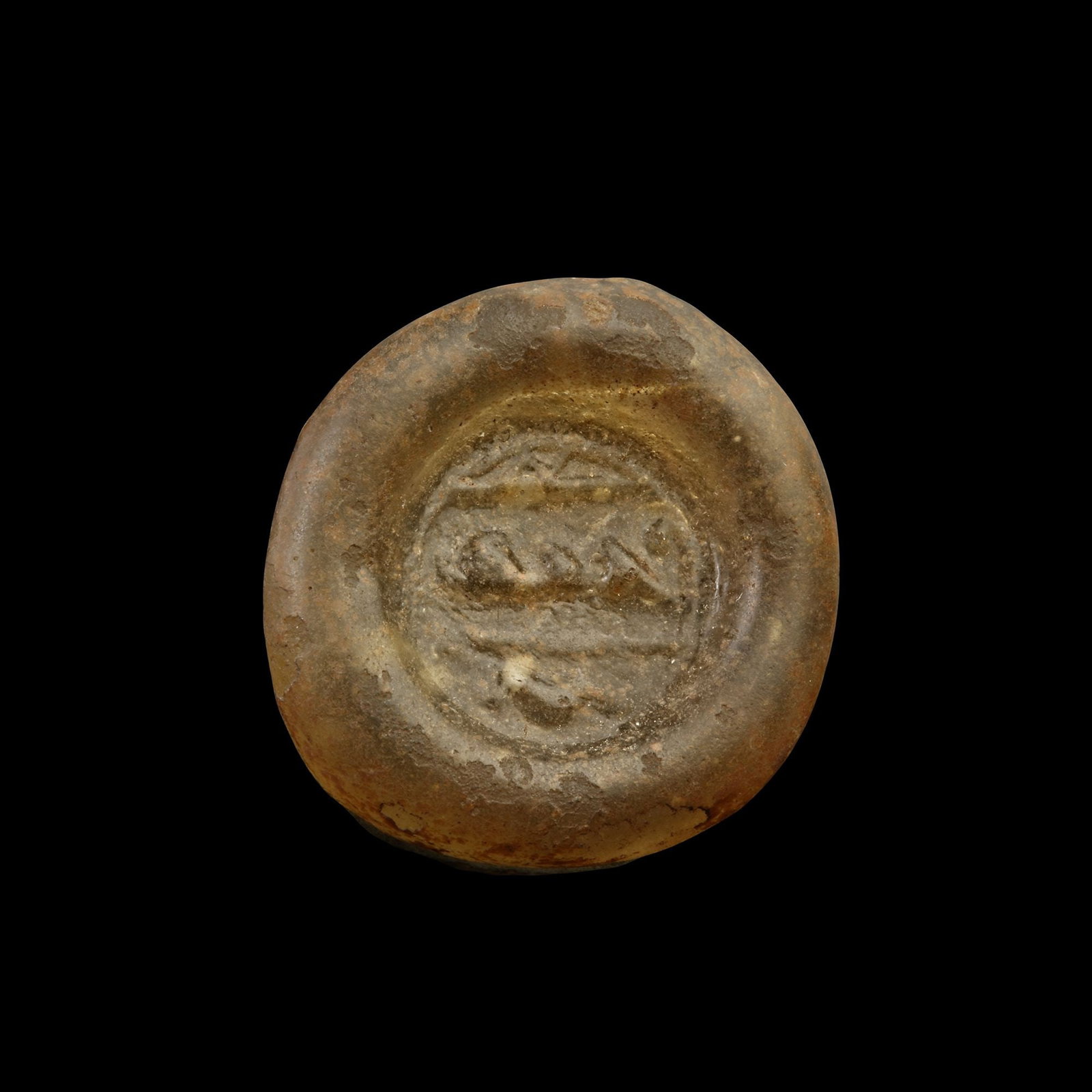 AN EARLY ISLAMIC GLASS WEIGHT OF DOUBLE DIRHAM, 10TH-11TH CENTURY: Glass weight, moulded and stamped, transparent light-brown in colour, citing in the centre with 3 lines of undeciphered Arabic text. 6.017g, 25 mm. coin weight: double dirham.