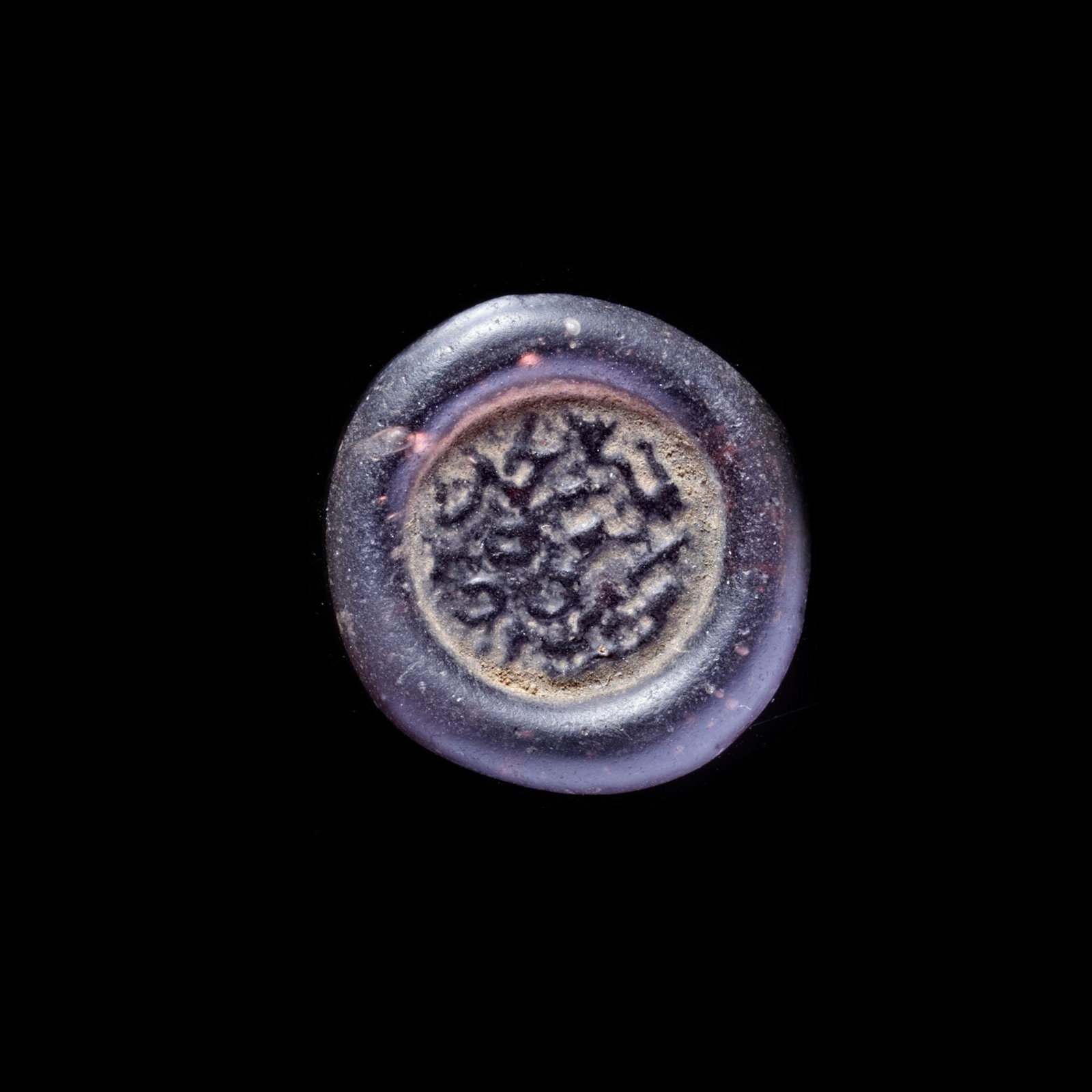 AN EARLY ISLAMIC GLASS WEIGHT OF DOUBLE DIRHAM, 10TH-11TH CENTURY: Glass weight, moulded and stamped, transparent pint-violet in colour, citing in the centre with" Muhammed al-Awdi the year 50", 6.047g, 27.2 mm, coin weight: double dirham. LP 1891/347, N155