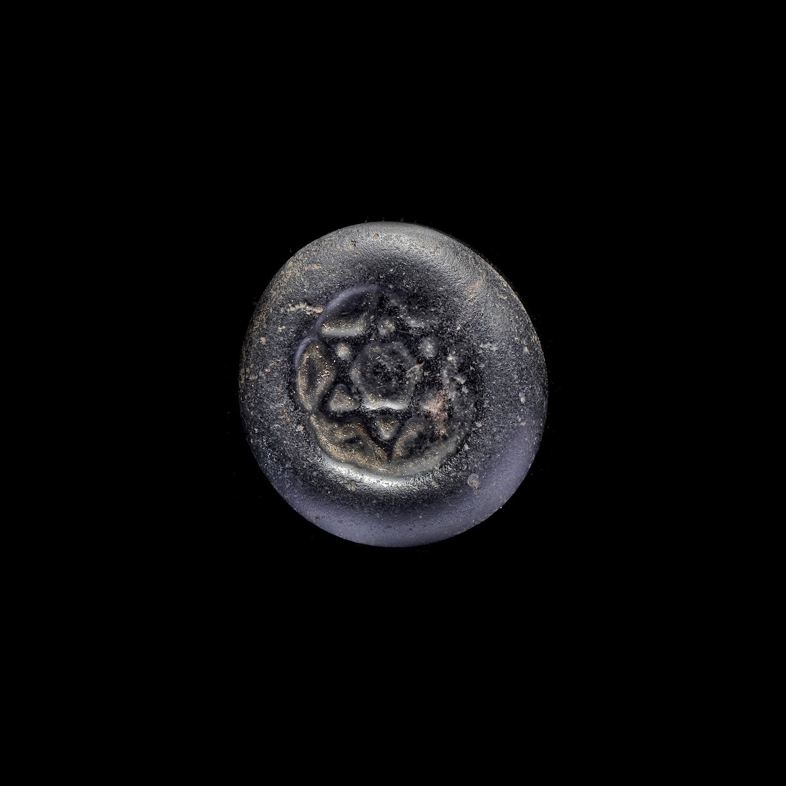 AN EARLY ISLAMIC GLASS WEIGHT OF DOUBLE DIRHAM, 10TH-11TH CENTURY: Glass weight, moulded and stamped, opaque black in colour, citing in the centre with the star of Solomon, 5.982g, 25 mm, coin weight: double dirham.