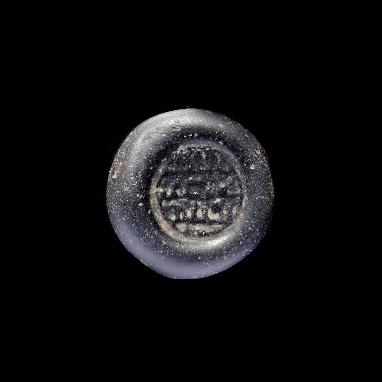 AN EARLY ISLAMIC GLASS WEIGHT OF DOUBLE DIRHAM, 10TH-11TH CENTURY: Glass weight, moulded and stamped, opaque black in colour, citing in the centre with 3 lines of undeciphered Arabic text. 5.983 g., 23 mm. coin weight: double dirham.