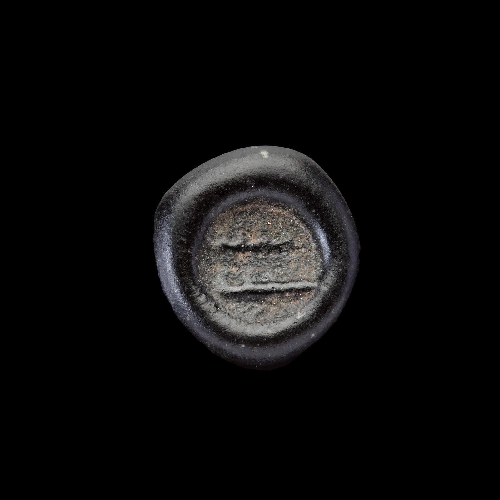 AN EARLY ISLAMIC GLASS WEIGHT OF HALF DIRHAM, 10TH-11TH CENTURY: Glass weight, moulded and stamped, opaque dark-black in colour, citing in the centre with 2 lines of undeciphered Arabic text. 1.506 g., 14 mm. coin weight: half dirham.