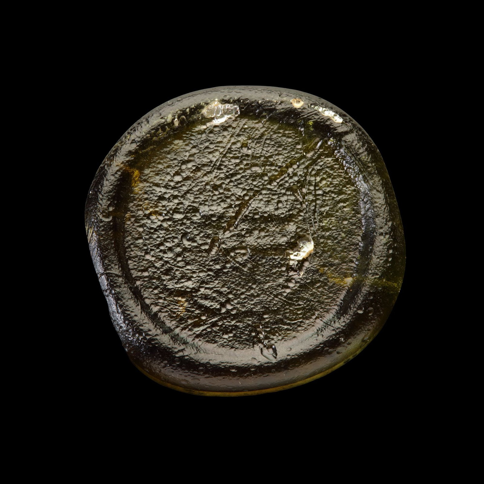 AN EARLY ISLAMIC GLASS WEIGHT OF DINAR, 10TH-11TH CENTURY: Glass weight, moulded and stamped, transparent light-green in colour, citing in the centre with 2 lines of undeciphered Arabic text. 4.21g, 25 mm. coin weight: dinar.
