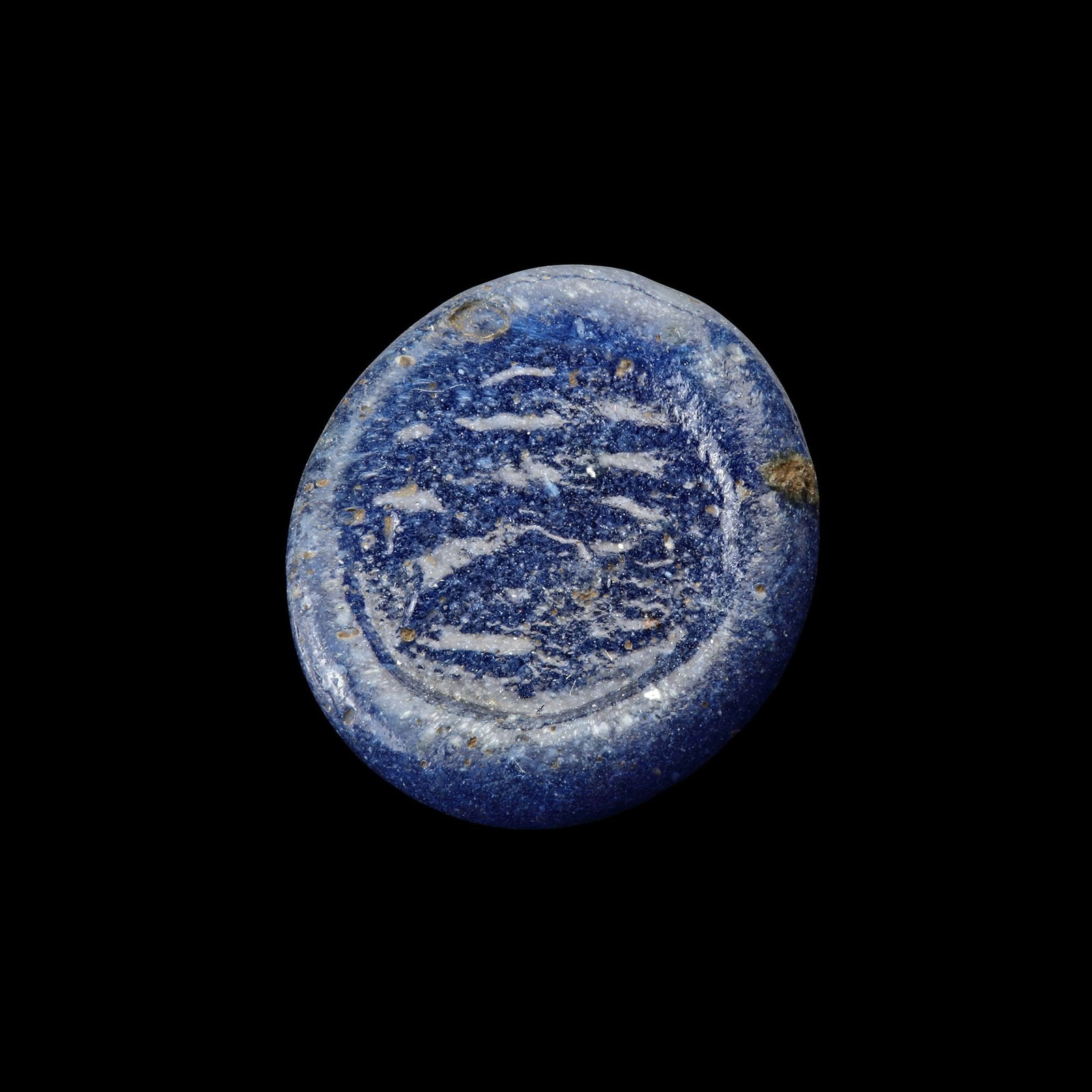 AN EARLY ISLAMIC GLASS WEIGHT OF HALF DIRHAM, 10TH-11TH CENTURY: Glass weight, moulded and stamped, opaque deep-blue in colour, citing in the centre with 2 lines of undeciphered Arabic text. 1.381g, 16 mm. coin weight: half dirham.