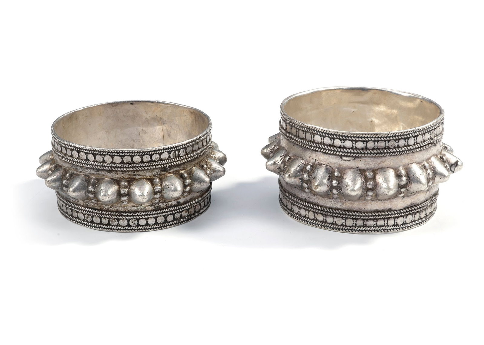 A PAIR OF SILVER BRACELETS, OMAN, 19TH CENTURY: Traditional Omani bracelets with bold raised decoration and fine silver detailing. 6,5 by 4 cm. 176 gr. THE DR. SAAD AL-JADIR COLLECTION