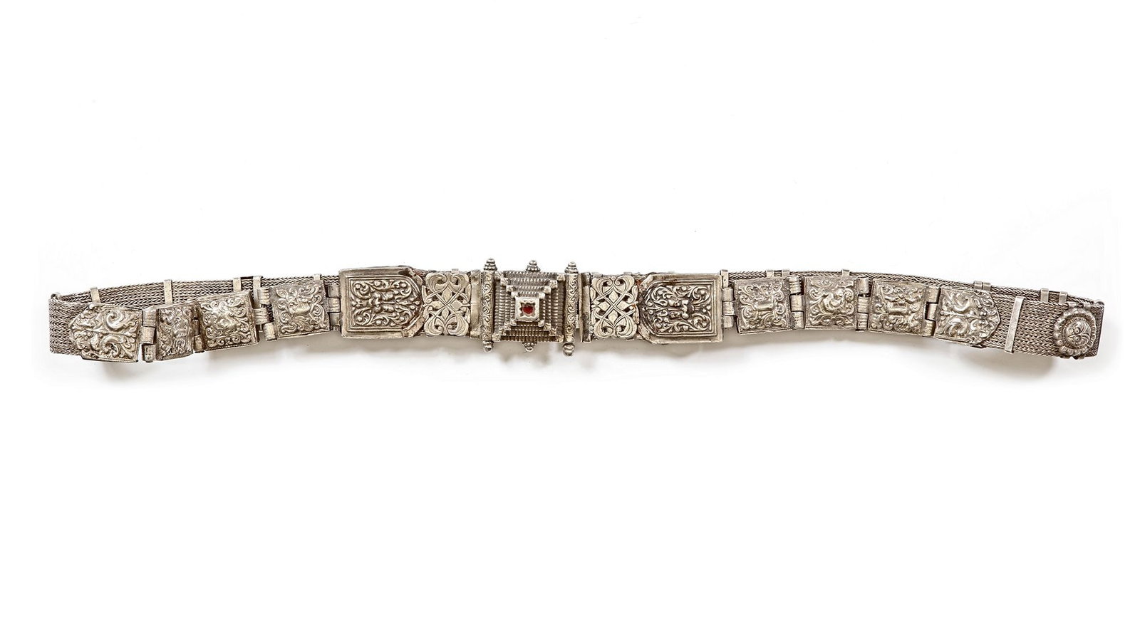 AN OTTOMAN SILVER BELT, 19TH CENTURY: Composed of richly decorated plaques with intricate repouss?© designs of floral and geometric motifs. The central clasp is square-shaped with a set red stone, framed by detailed ornamentation. 90 cm.