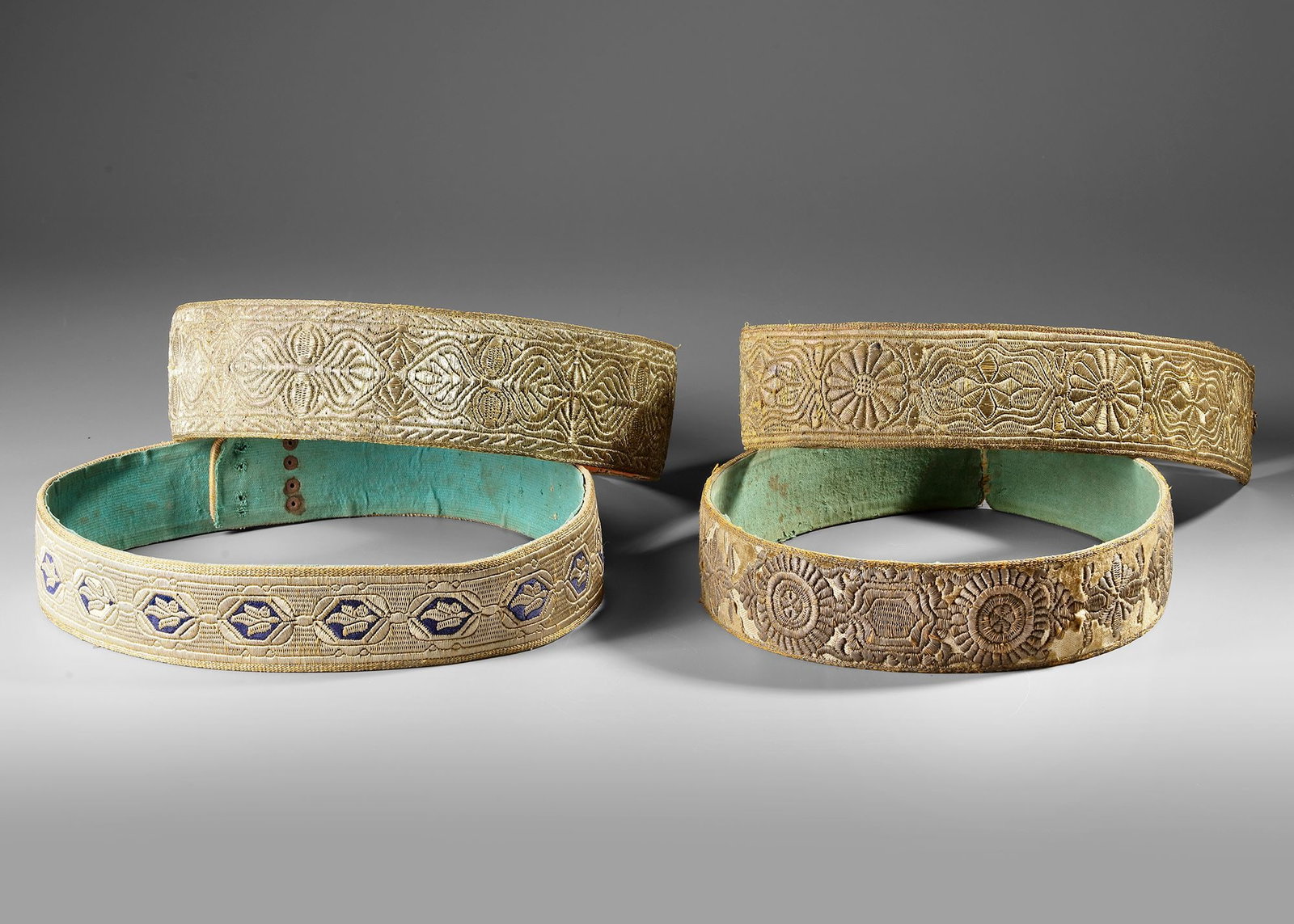 FOUR EMBROIDERED YEMENI BELTS, 19TH CENTURY: These four antique belts feature finely detailed hand-embroidery characteristic of 19th-century Yemeni craftsmanship. Each belt displays unique geometric and floral motifs worked in metallic thread on