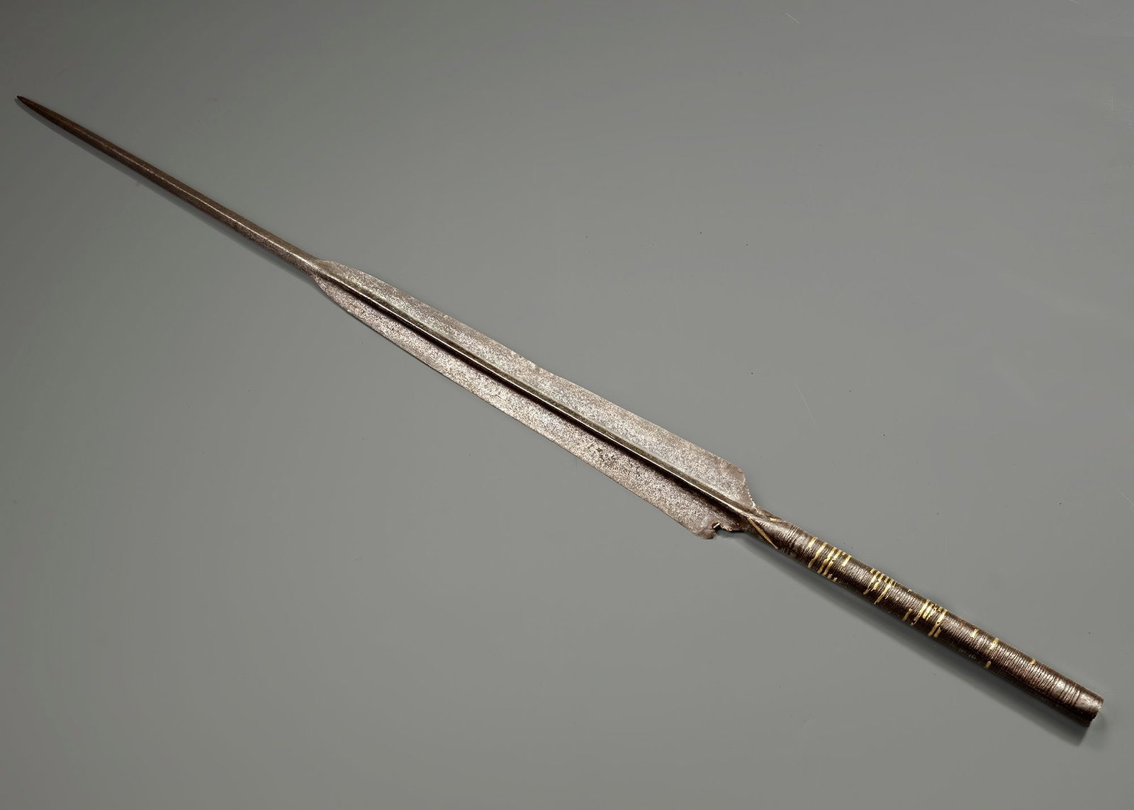 A SPEAR POINT YEMEN, 15TH CENTURY: A 15th-century Yemeni spear point forged in steel, featuring a long, tapering blade with a pronounced central ridge for strength and balance. The elegant, leaf-shaped form narrows to a sharp tip, desi