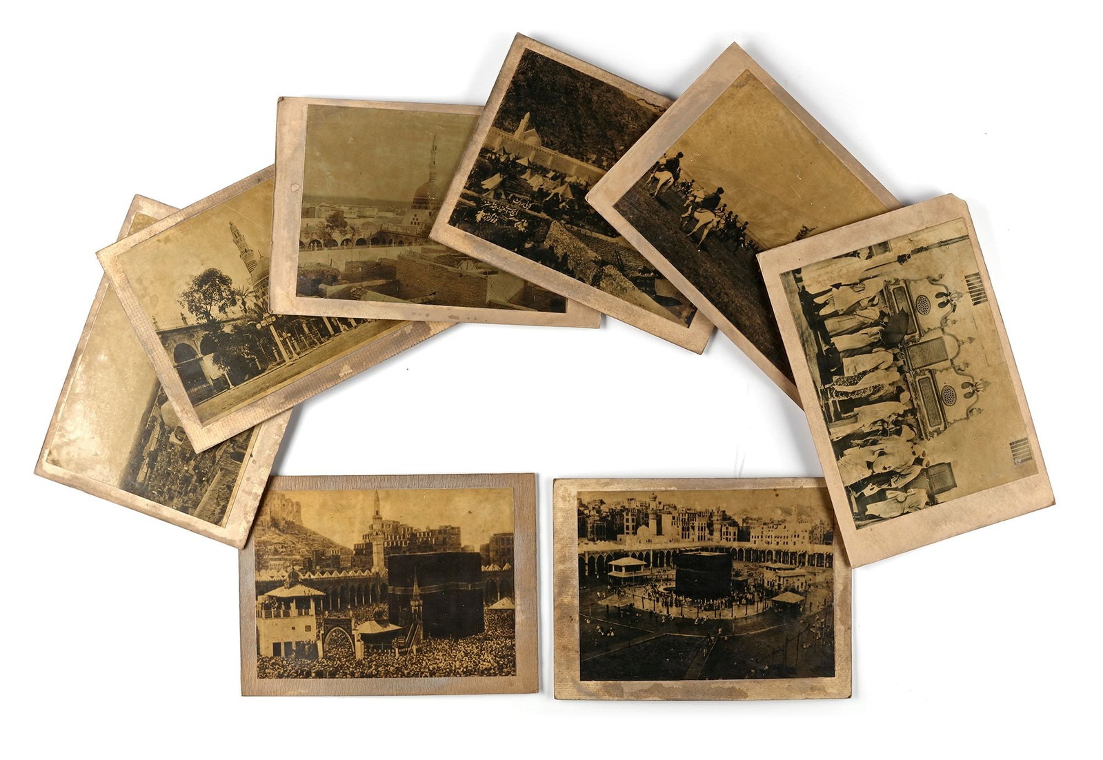 A COLLECTION OF EIGHT OLD PHOTOGRAPHS OF MECCA, MEDINA, MUNA AND THE HAJJ, EARLY 20TH CENTURY: Two images of vast crowds of prayers around the Kaaba in Mecca, image of an Ottoman caravan during the procession of the mahmal, picture of the pilgrim's tents at Muna, two pictures of the view of al-