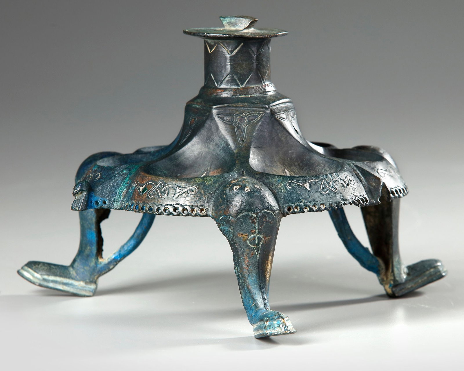 A KHORASAN SILVER INLAY LAMP STAND BASE, PERSIA, 12TH CENTURY: On three hoof feet, the features defined with inlaid silver with drop shaped cartouches Silver-inlay. Height: 23 cm.